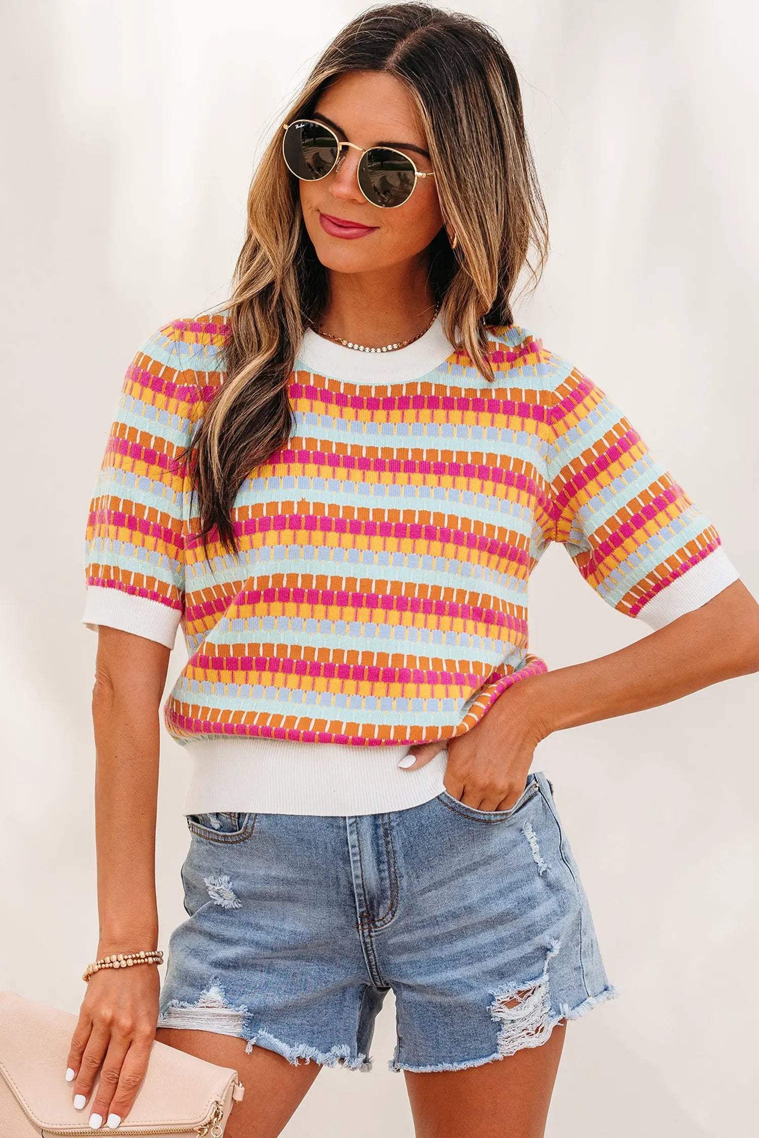 Woman wearing vibrant orange striped knit sweater with short sleeves and fuchsia pink rib details