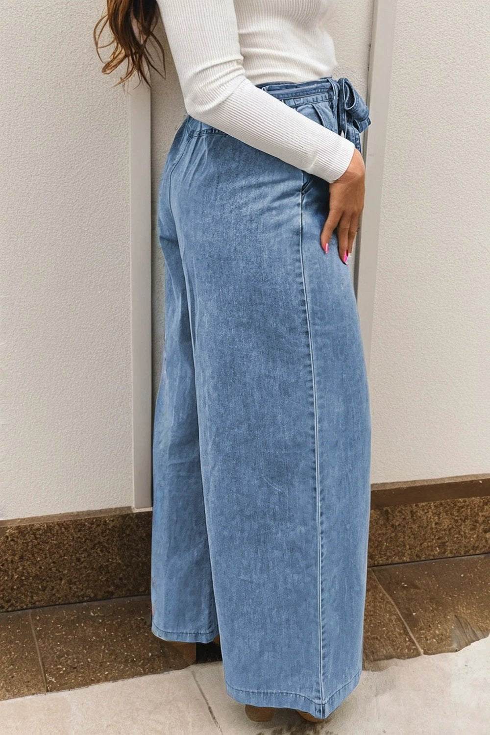 Woman wearing acid-washed bow knot sash wide leg jeans styled for casual chic look