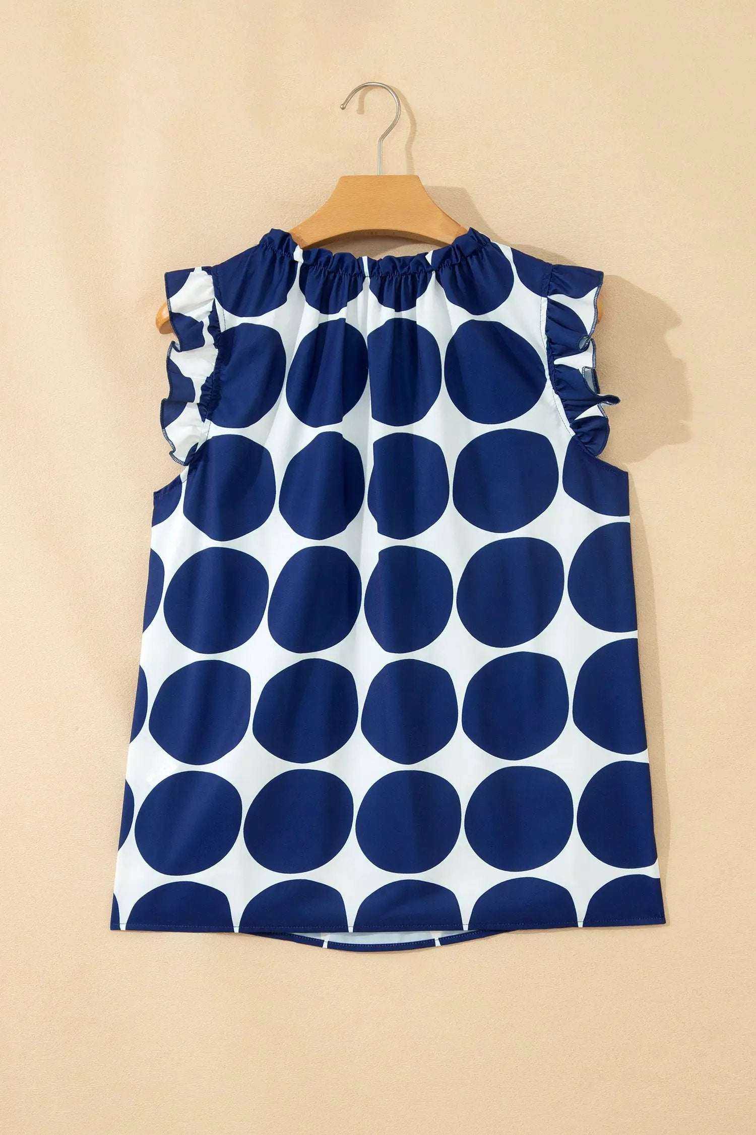 Blue and white polka dot tank top with frilled round neckline and shoulder ruffles on breathable fabric