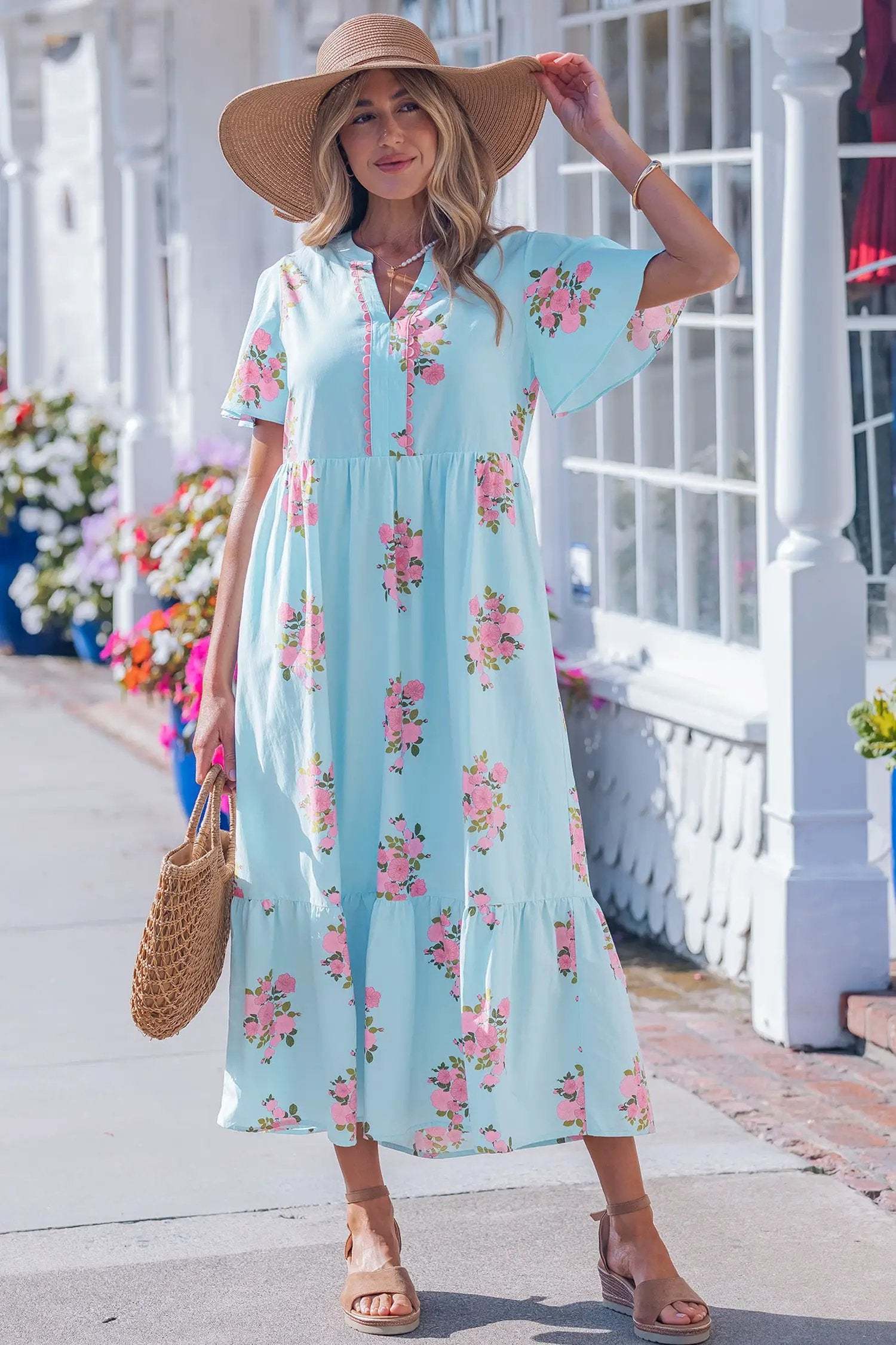 Woman wearing pink floral maxi dress with notched neck and flutter sleeves outdoors