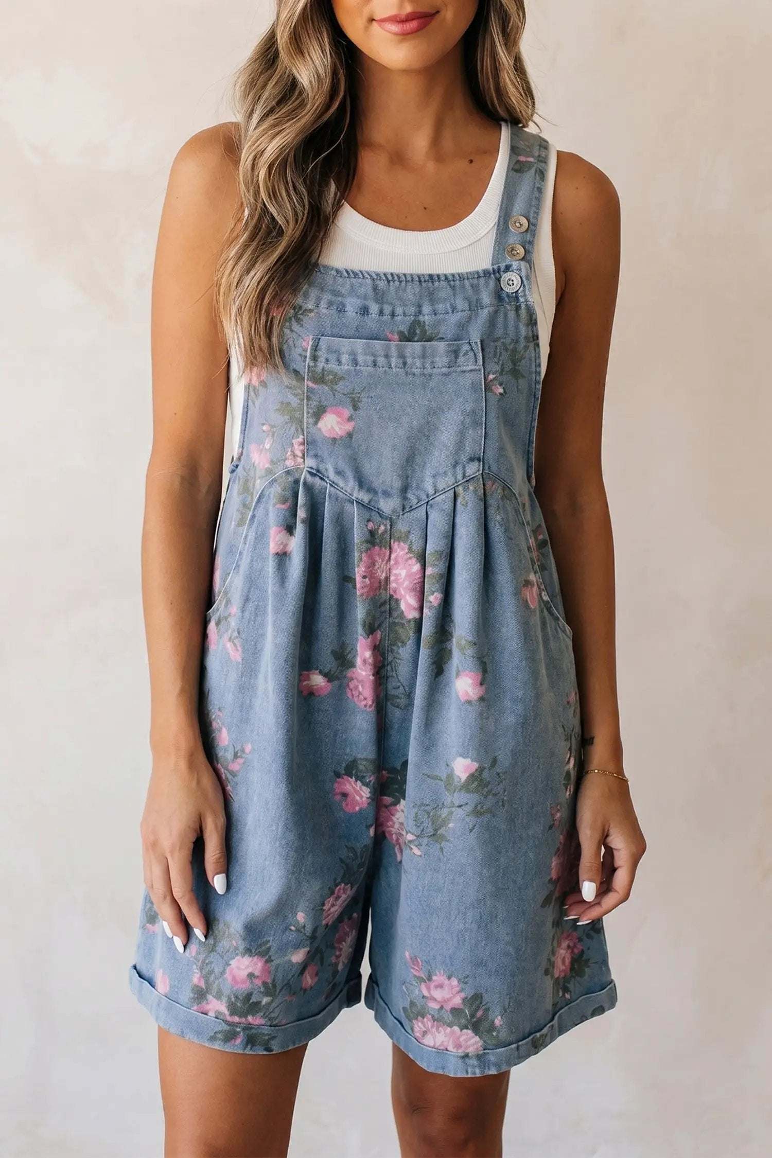 Woman wearing floral print denim shortalls with adjustable straps and front bib pocket