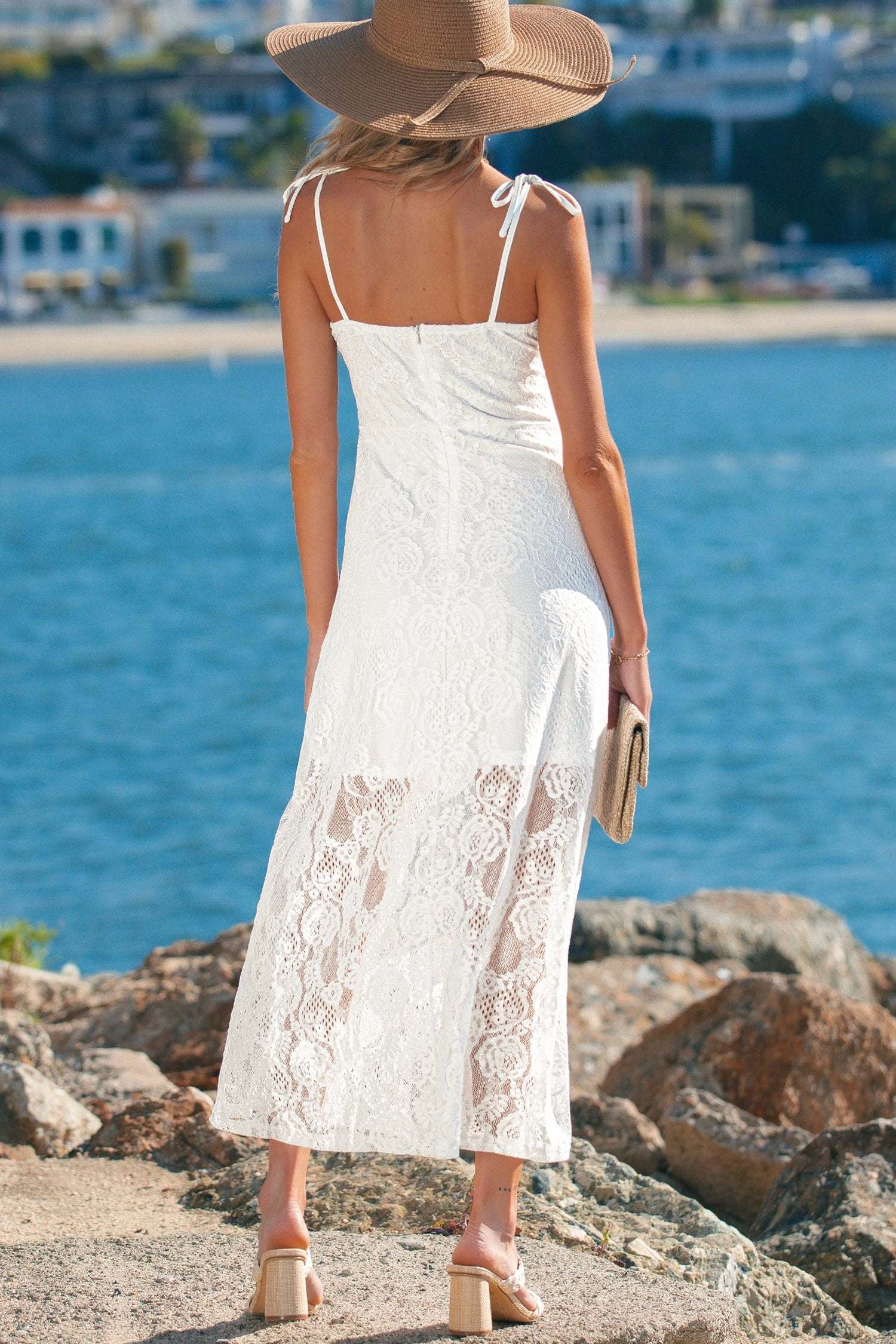 Woman wearing floral lace overlay maxi dress with spaghetti straps outdoors in sunlight