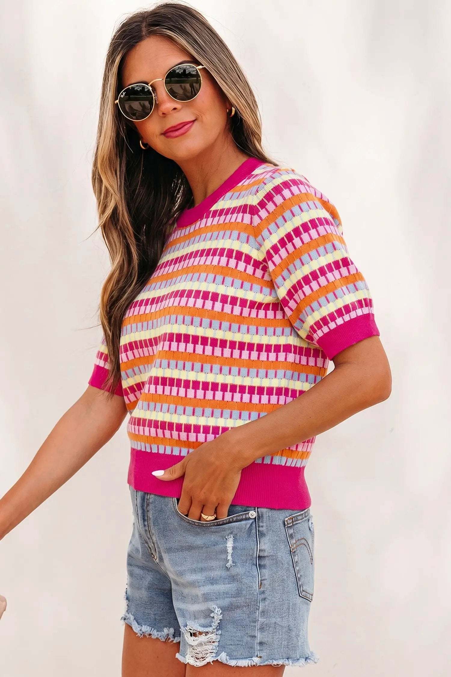 Woman wearing orange striped knit sweater with short sleeves and fuchsia pink rib neckline