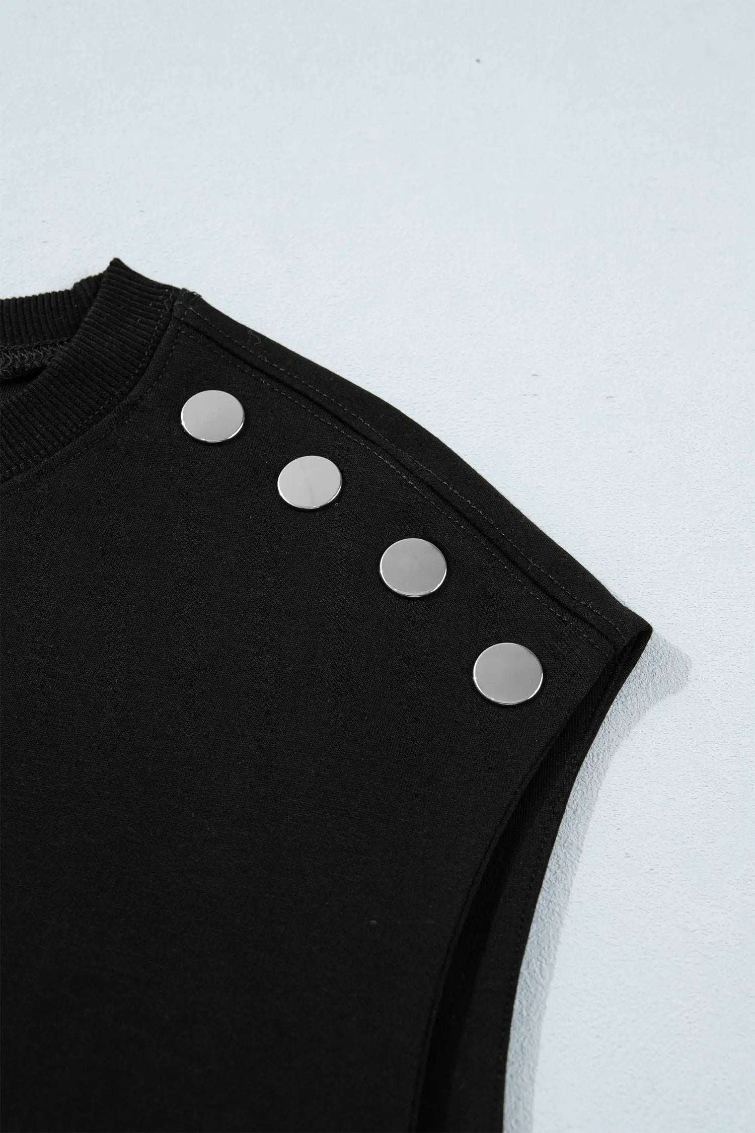 Woman wearing effortless chic mom black short sleeve top with metal button details