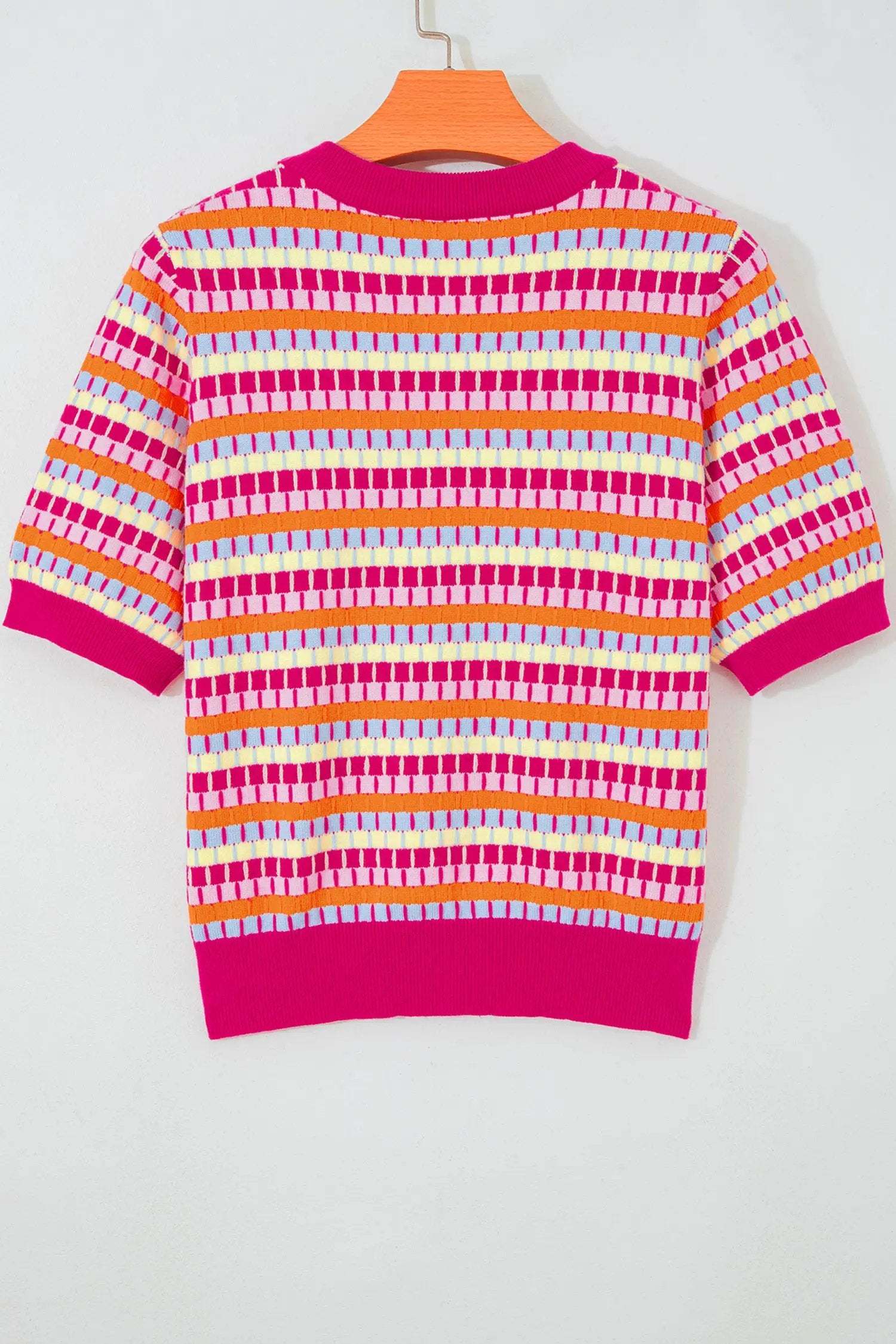 Woman wearing a vibrant orange striped knit sweater with short sleeves and fuchsia pink ribbed neckline and cuffs