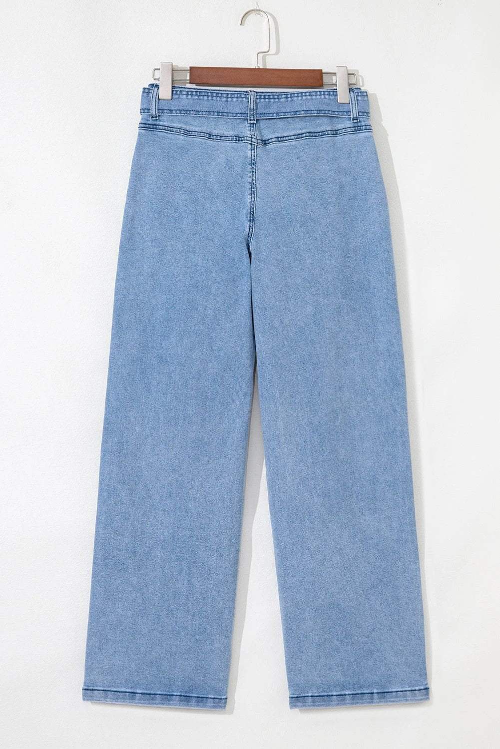 Woman wearing acid washed bow knot sash wide leg jeans with vintage finish and adjustable waist.