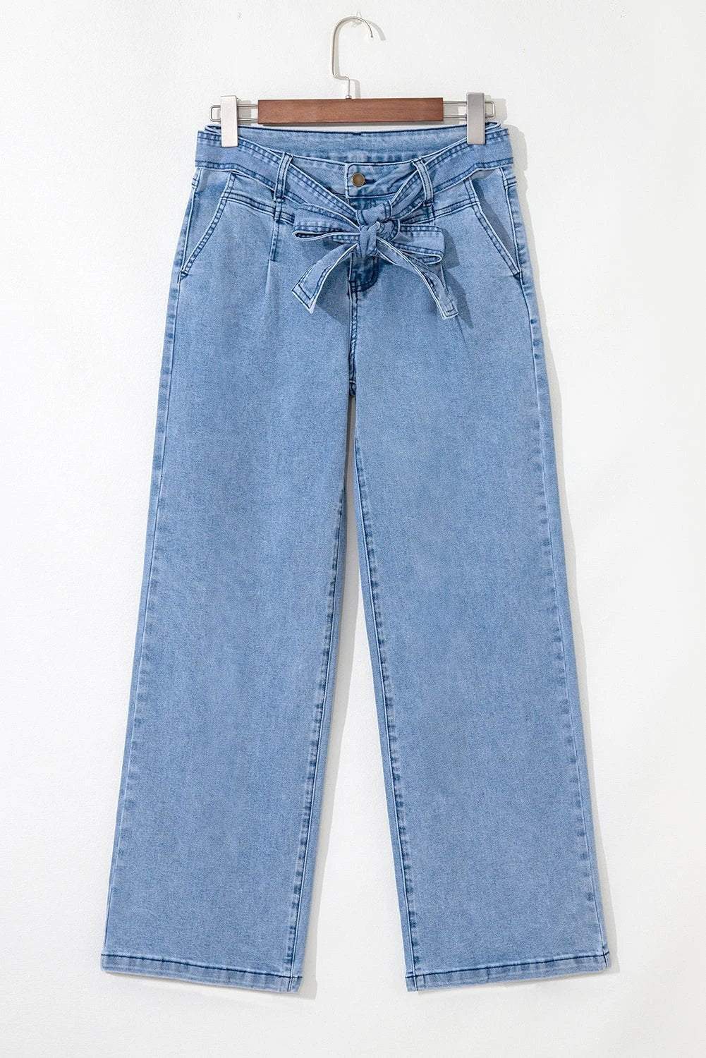 Woman wearing acid washed bow knot sash wide leg jeans with vintage texture and adjustable waist detail