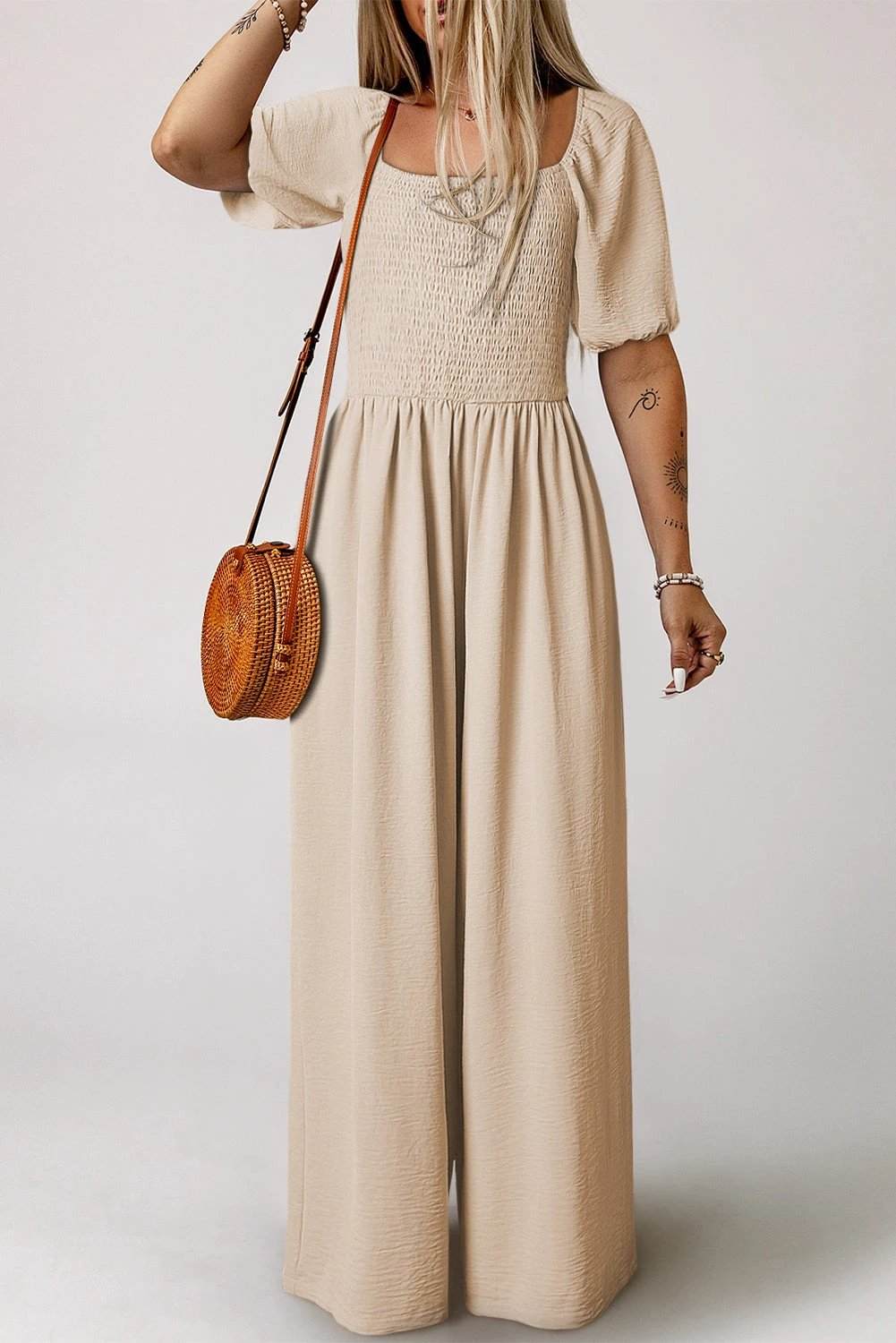 Woman wearing bubble sleeve smocked wide-leg jumpsuit with square neckline and flowy silhouette