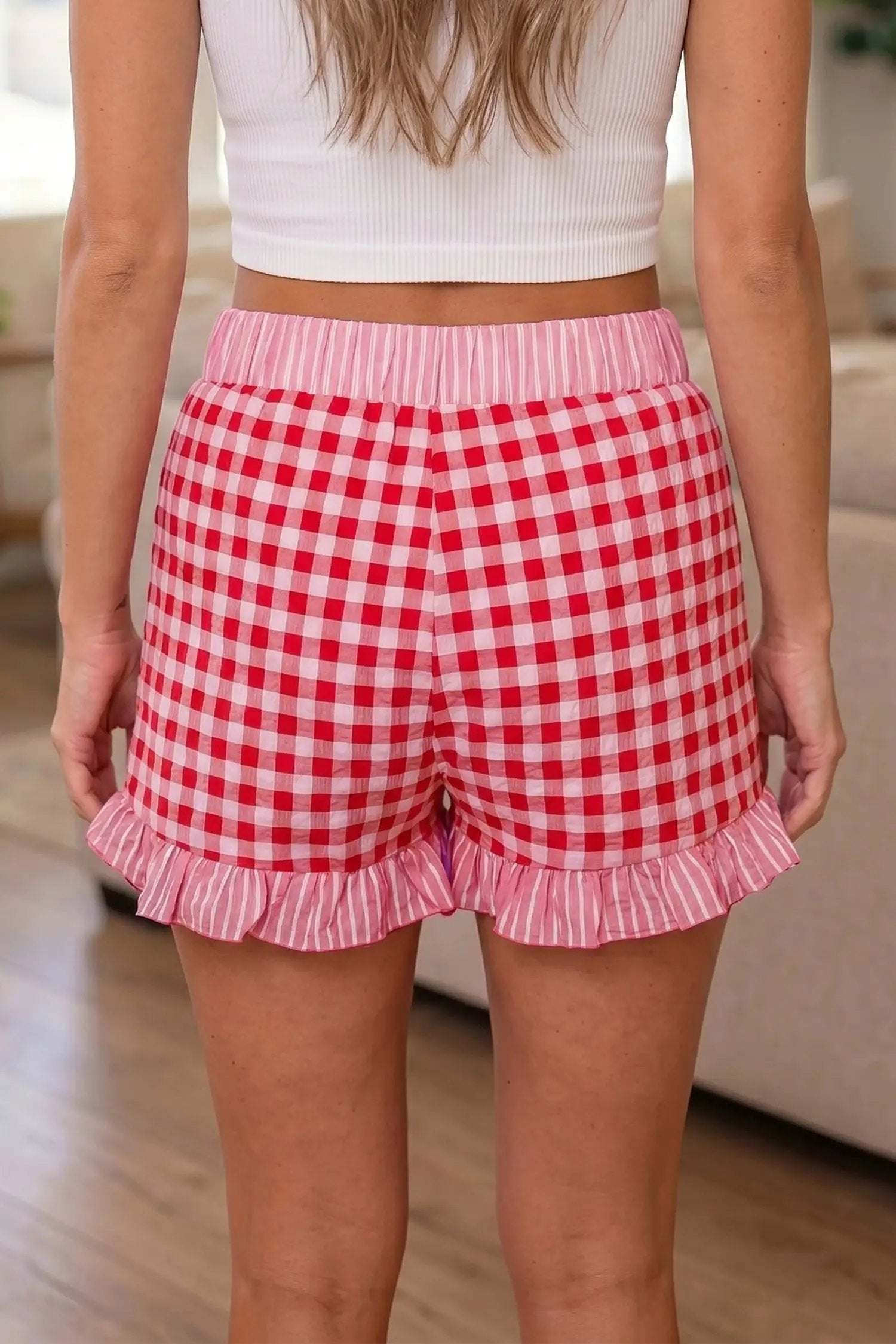 Woman wearing gingham ruffle hem shorts with lace tie waist detail in casual weekend outfit