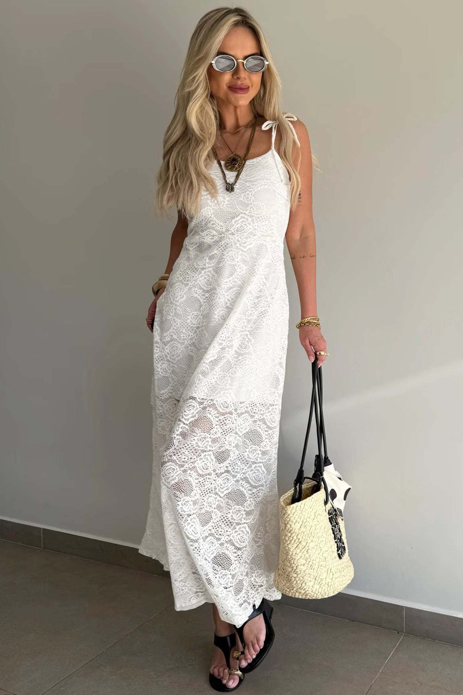 Woman wearing a floral lace overlay maxi dress with spaghetti straps and scalloped edges