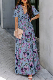 Woman wearing a sky blue floral print maxi dress with frilled V-neck and short flutter sleeves