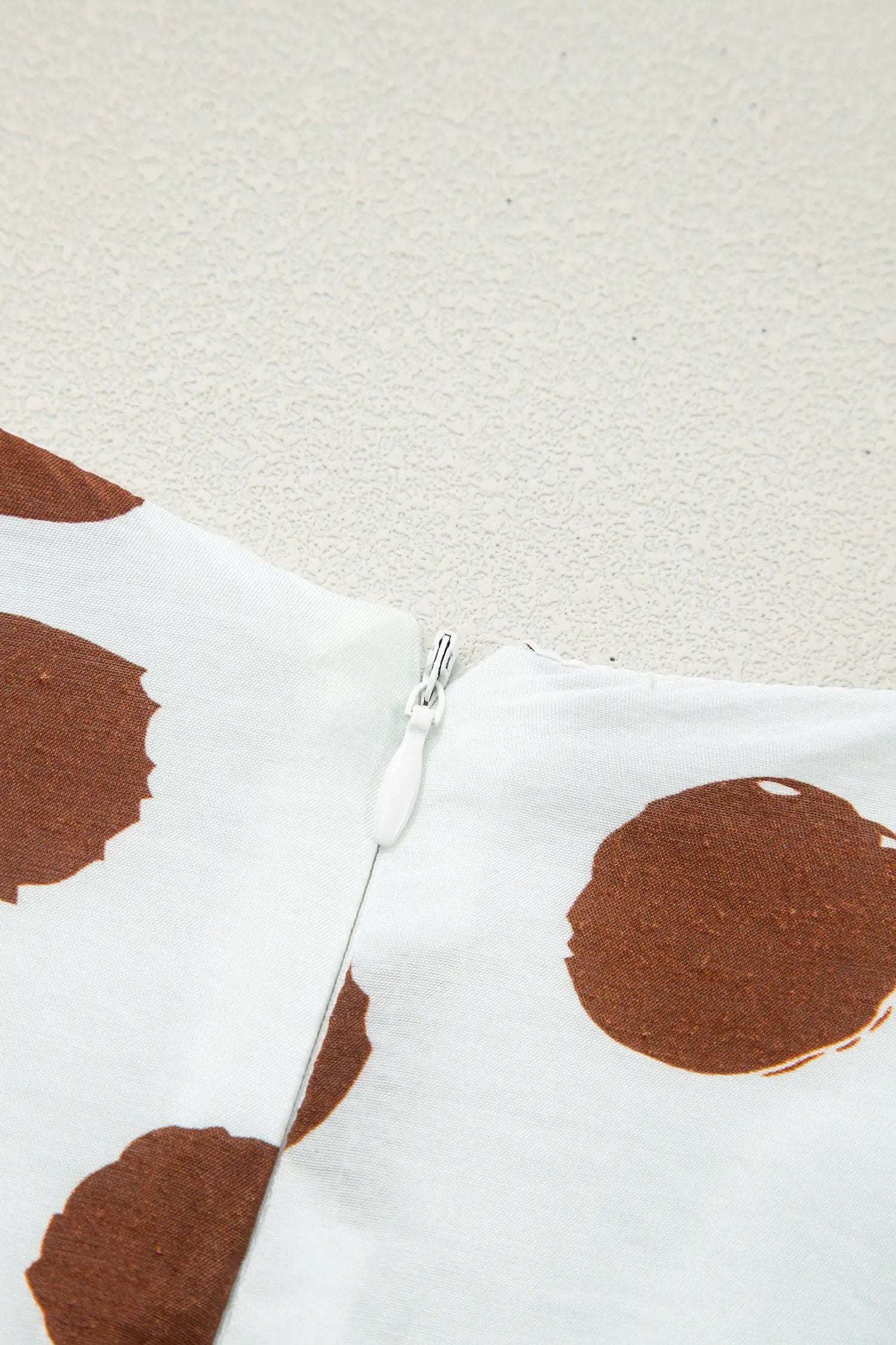 White midi dress with brown polka dots, V-neck, short sleeves, and tie waist design