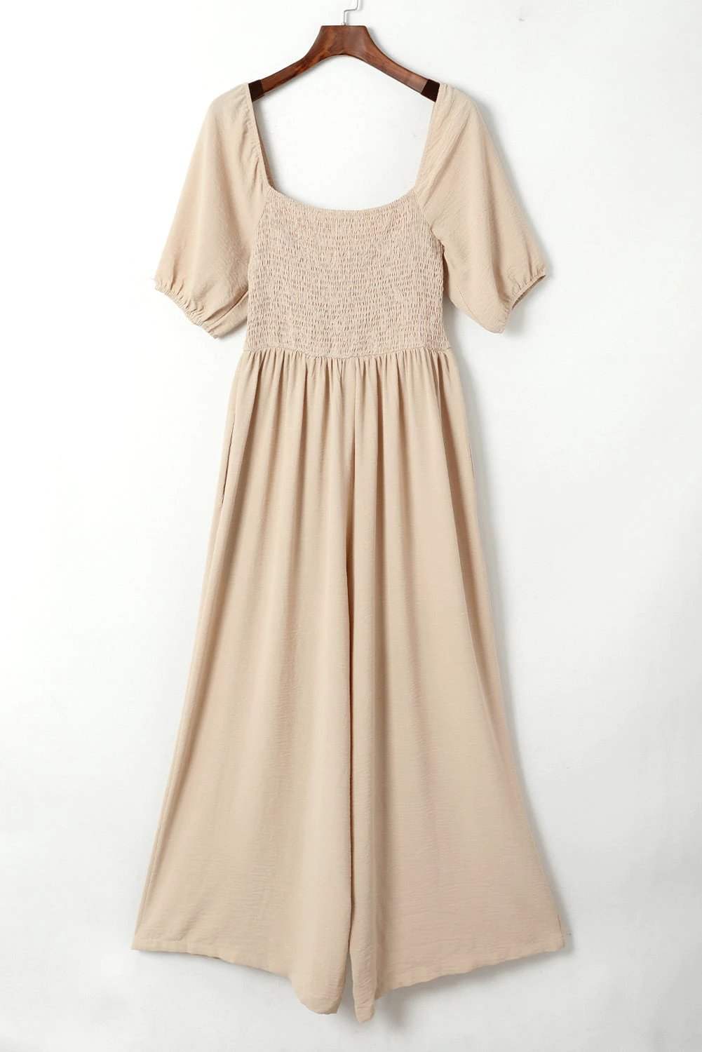 Woman wearing a bubble sleeve smocked wide-leg jumpsuit with a relaxed fit and square neckline