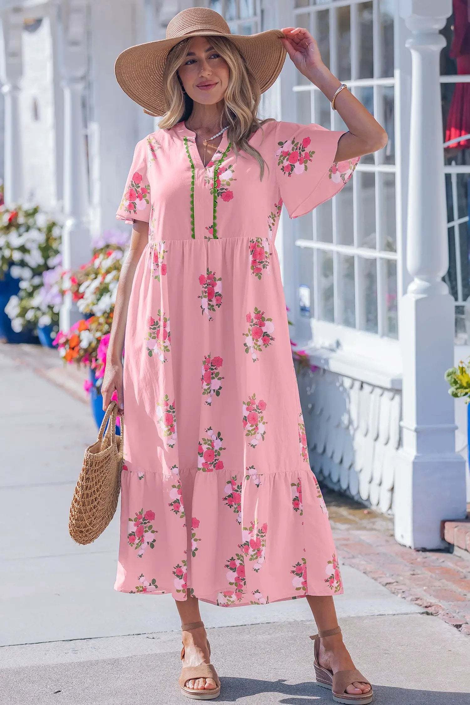 Woman wearing a pink floral maxi dress with notched neck and flutter short sleeves