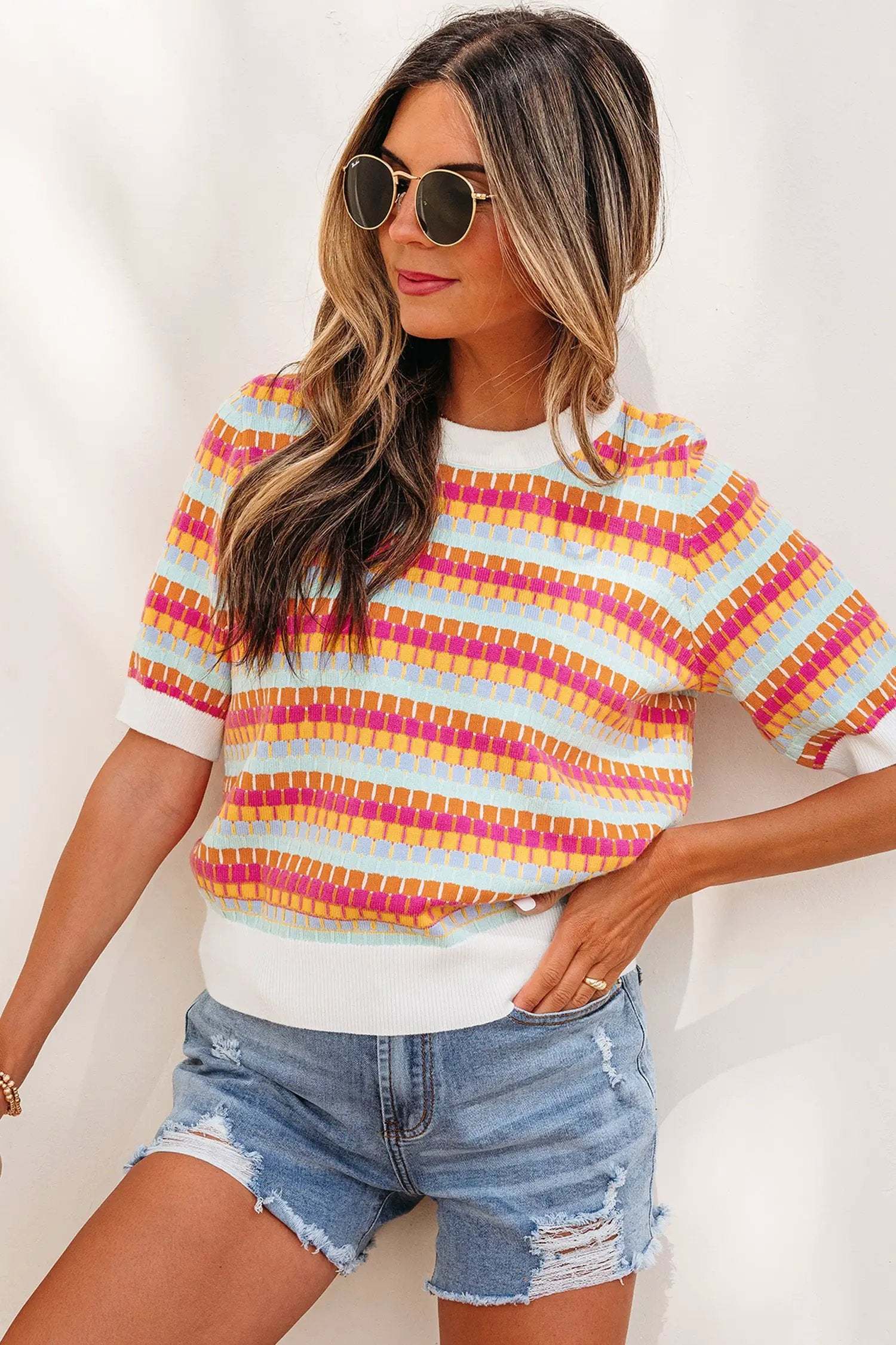 Woman wearing orange striped knit sweater with abstract stripes and fuchsia pink rib details
