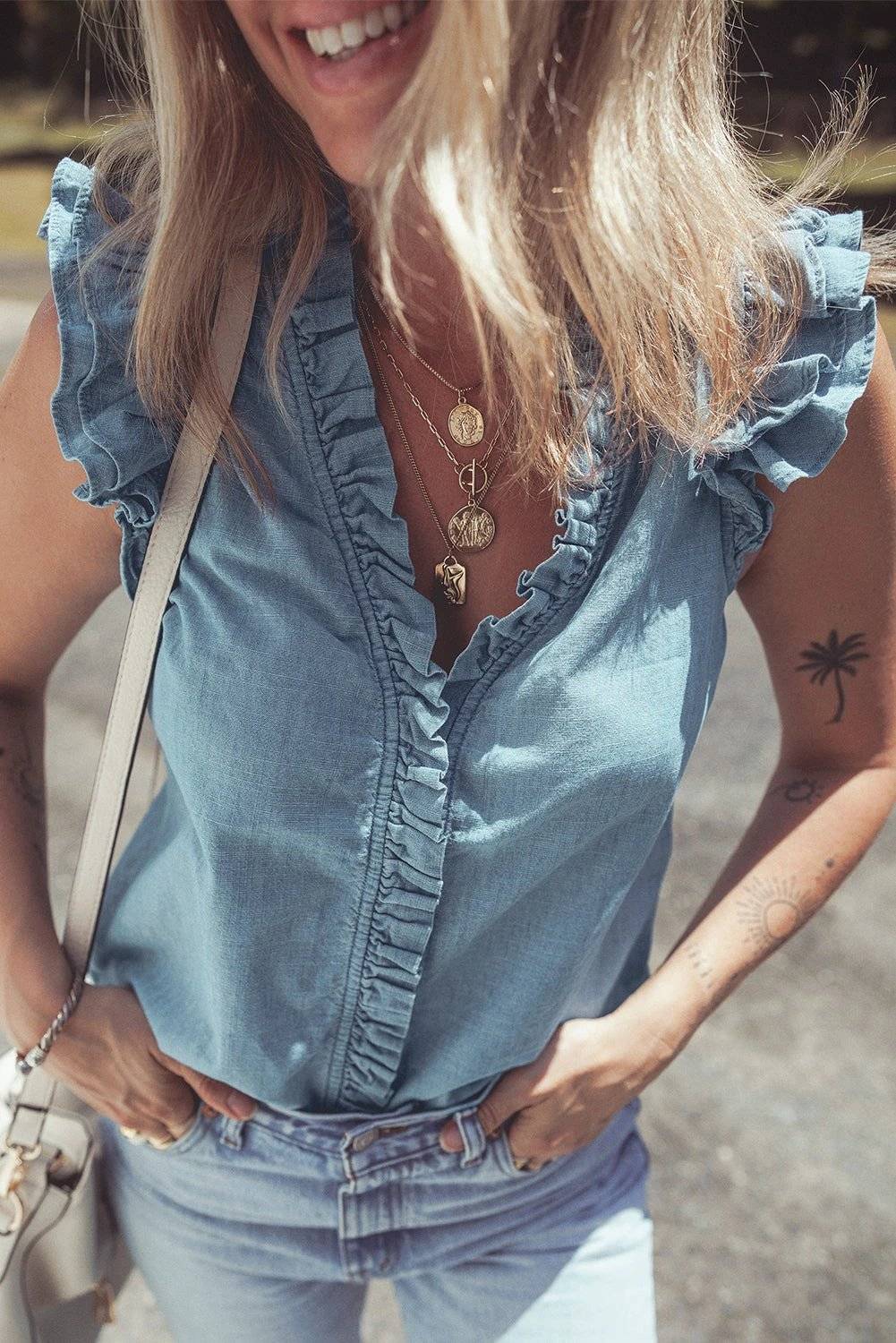 Woman wearing a chic mom energy frilly ruffle trim V-neck chambray tank top
