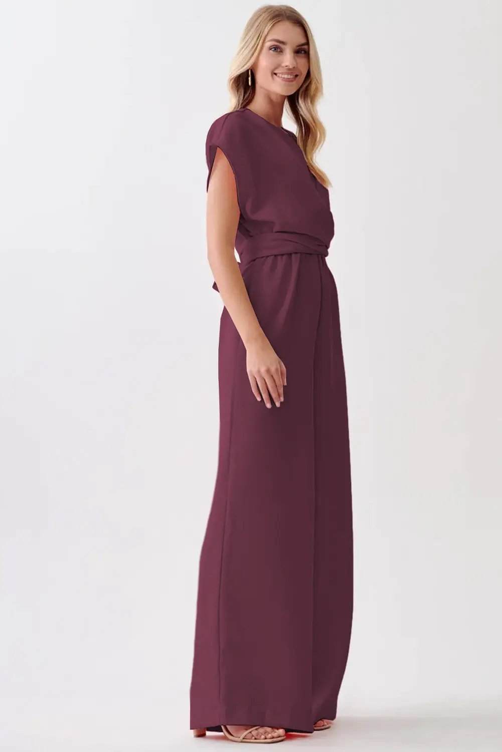 Woman wearing a wine-colored knot-waist cap sleeve jumpsuit with wide-leg silhouette