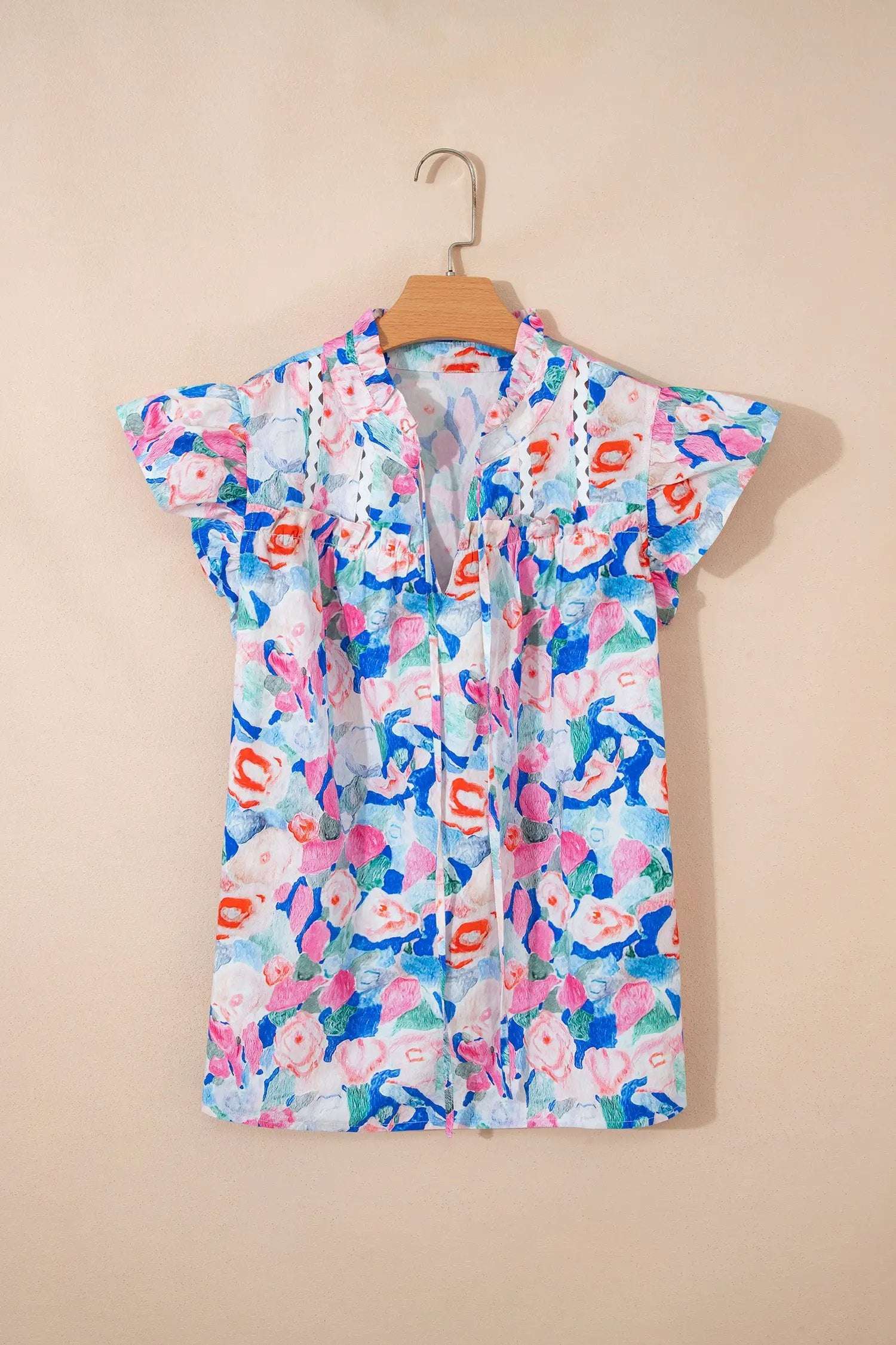 Woman wearing Vacation Vibe floral print tie neck blouse with V neck and ruffle short sleeves