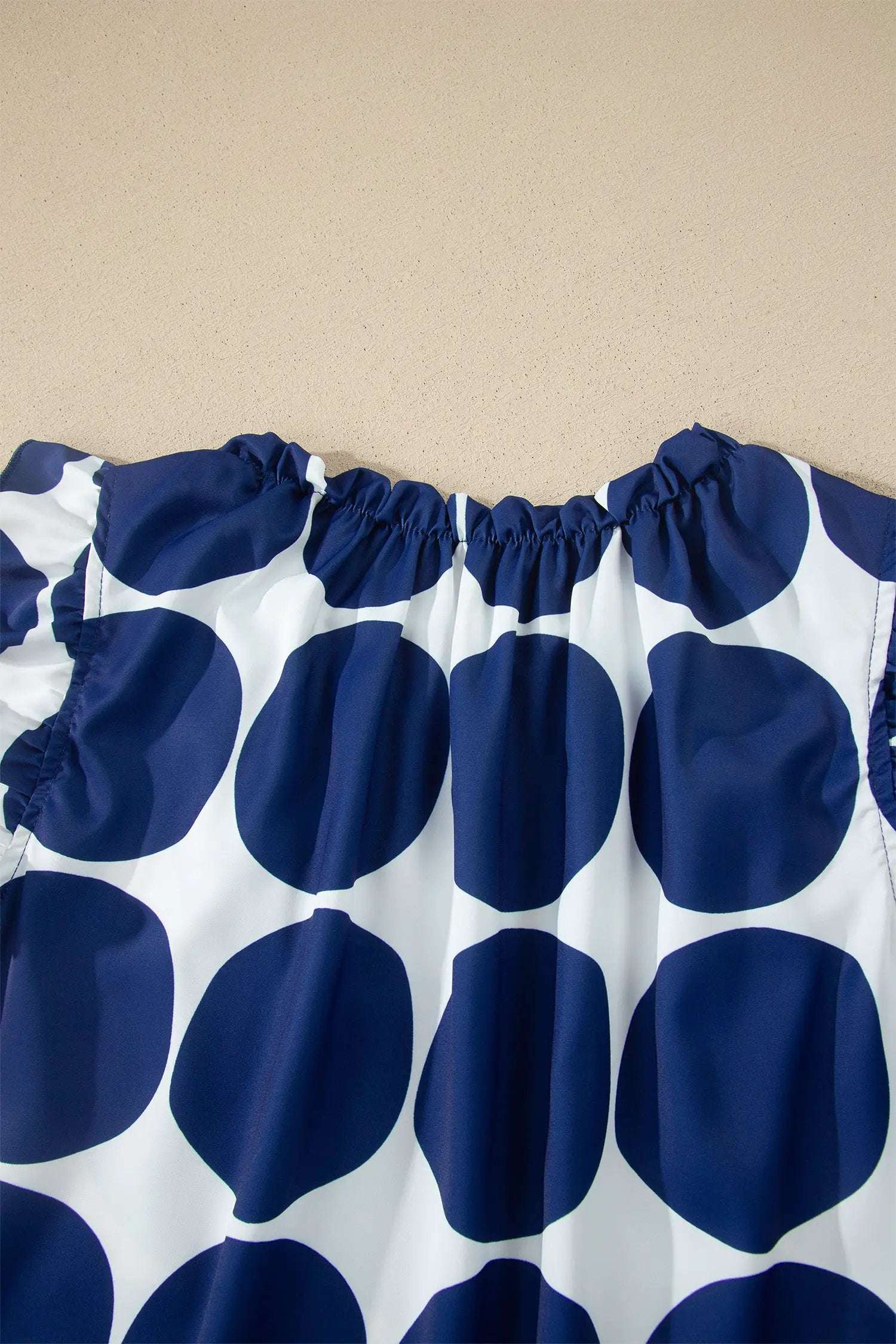 Blue and white polka dot sleeveless tank top with frilled round neck and shoulder ruffles