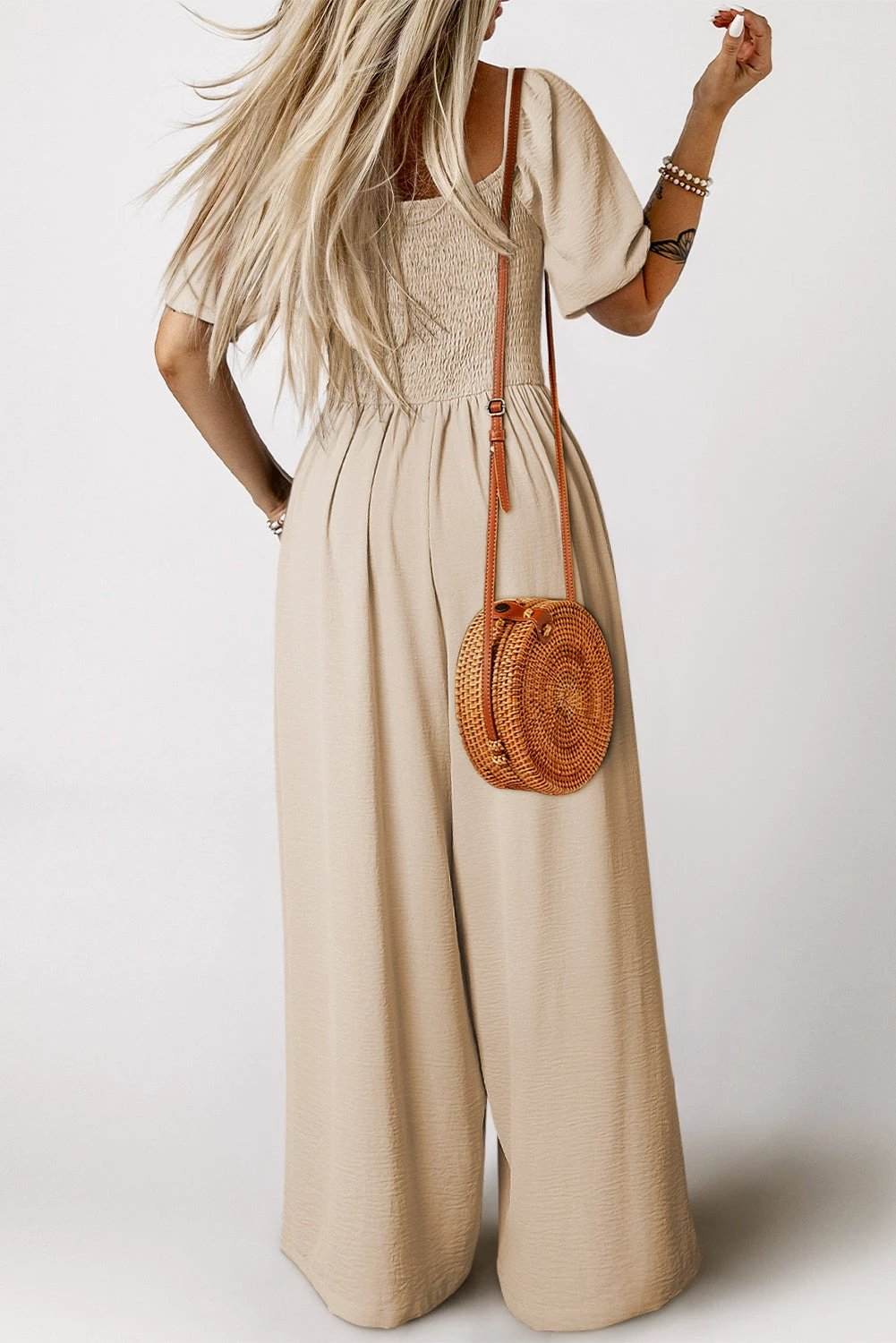 Woman wearing bubble sleeve smocked square-neck wide-leg jumpsuit in breathable fabric