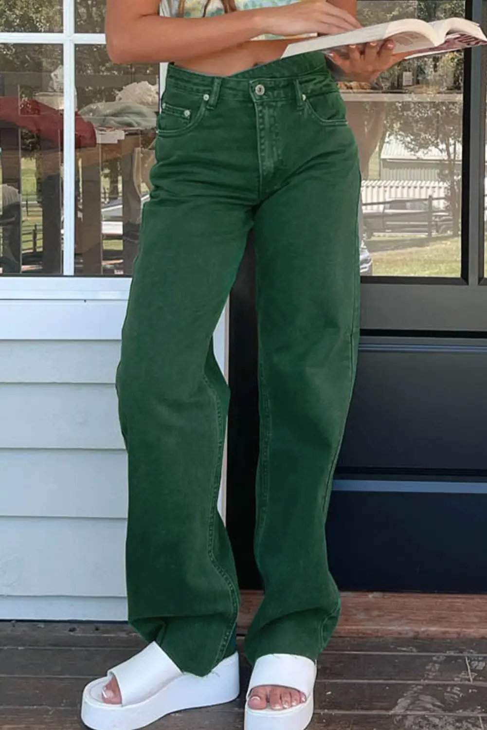 Model wearing crossed waist raw-hem jeans with a relaxed straight-leg fit and western-inspired silhouette