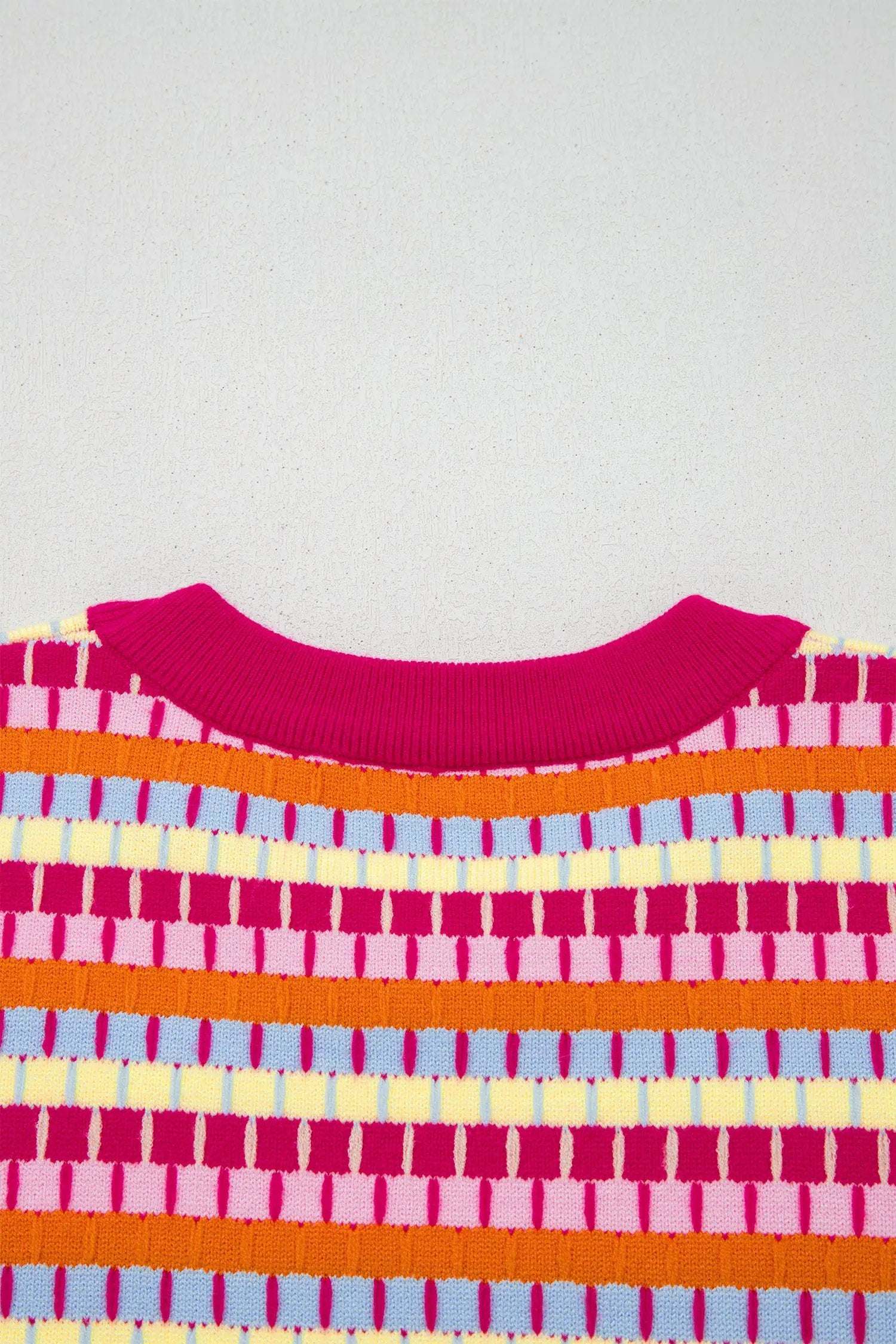 Close-up of vibrant orange striped knit sweater with short sleeves and fuchsia pink ribbed neckline and cuffs