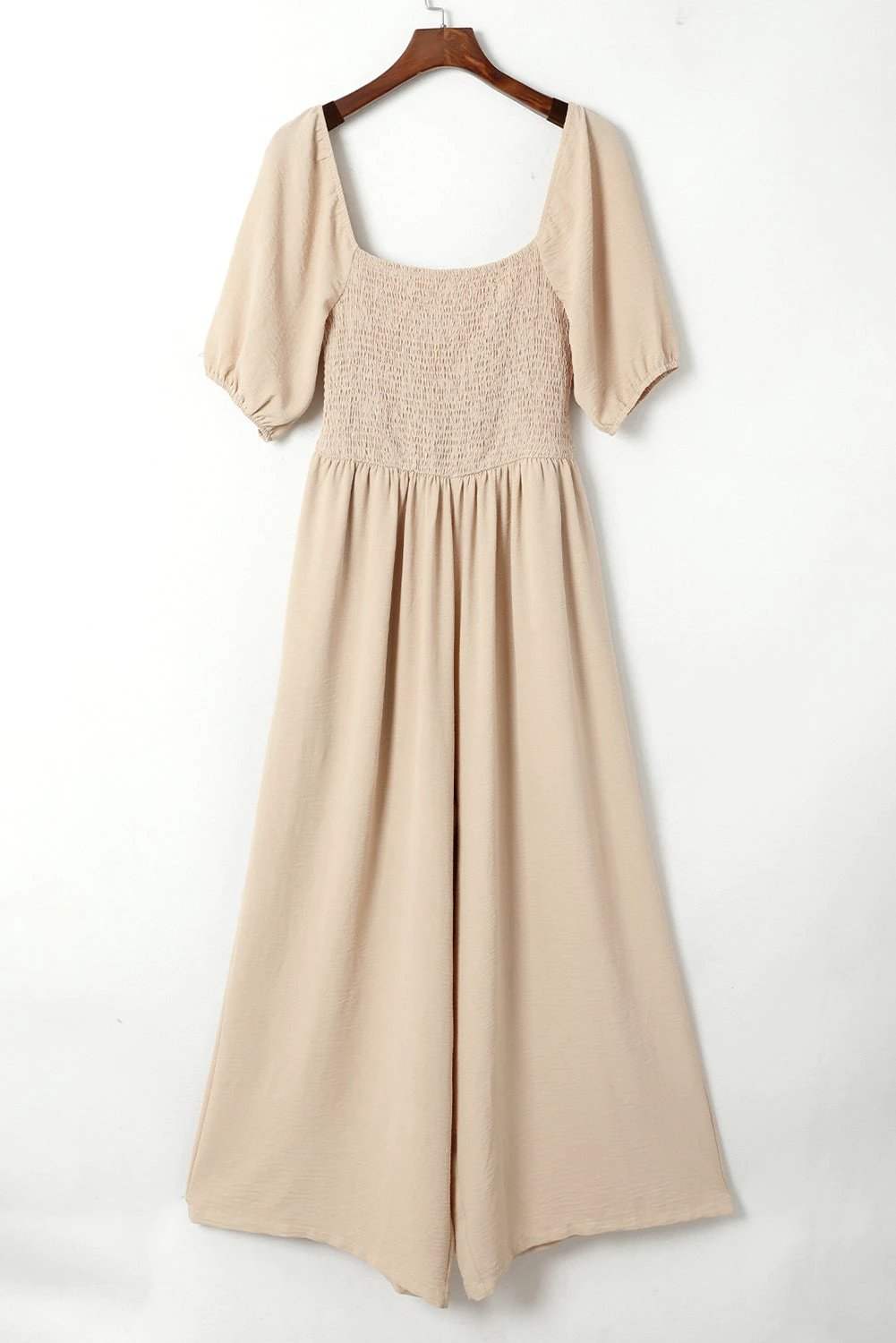 Woman wearing a bubble sleeve smocked wide-leg jumpsuit with square neckline and relaxed fit