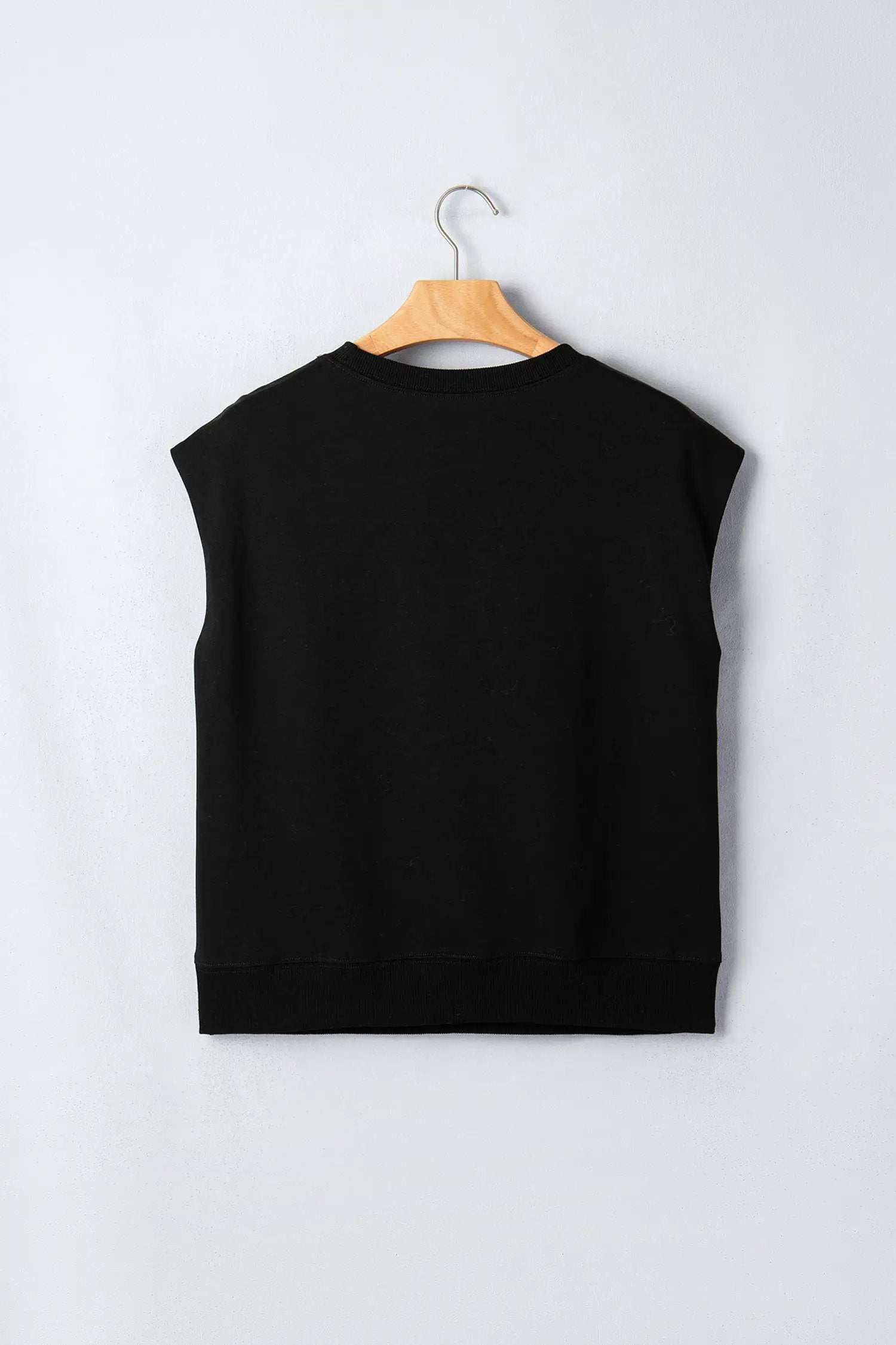 Woman wearing effortless chic mom short sleeve top with metal button details in black