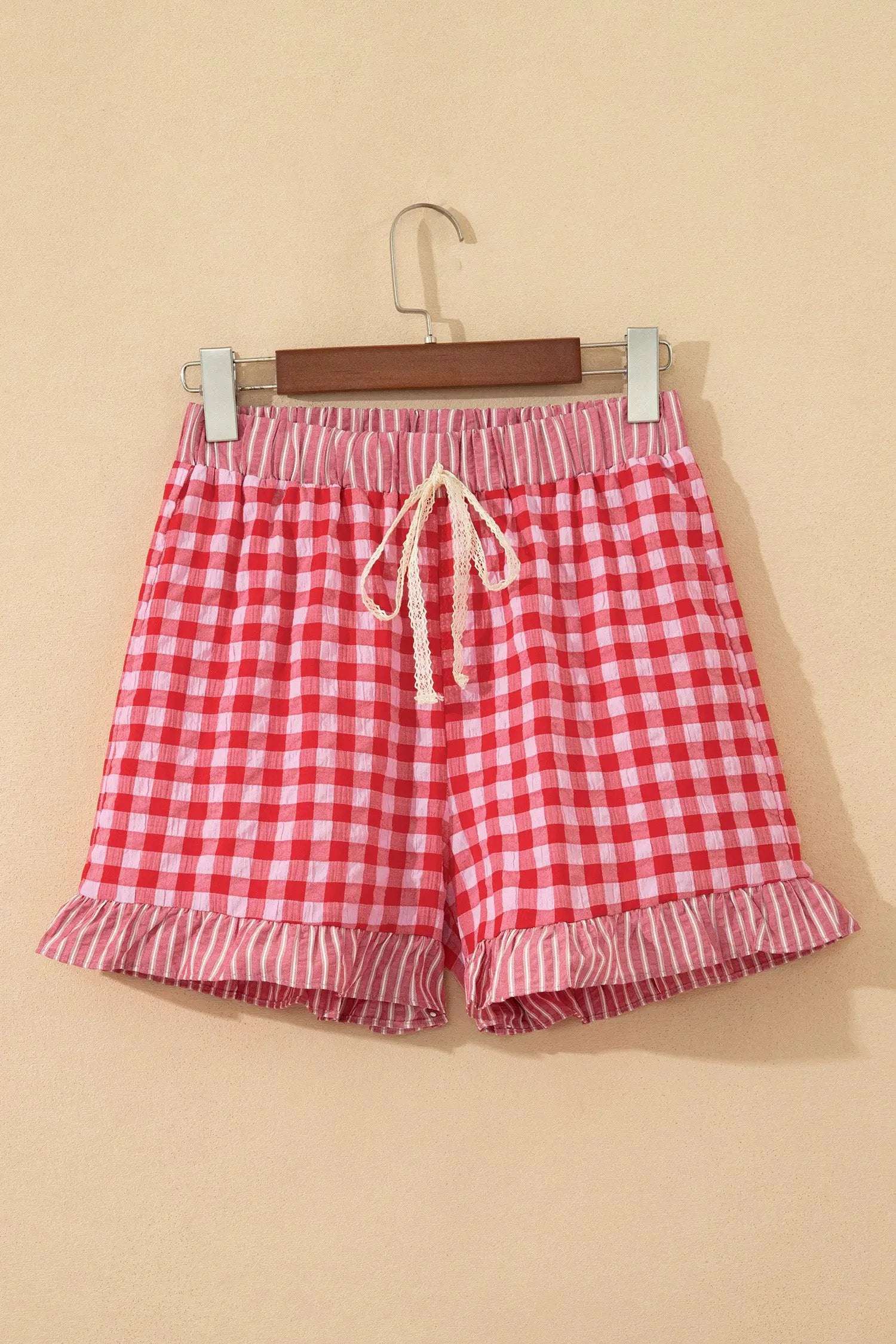 Woman wearing gingham ruffle hem shorts with lace tie waist detailing.