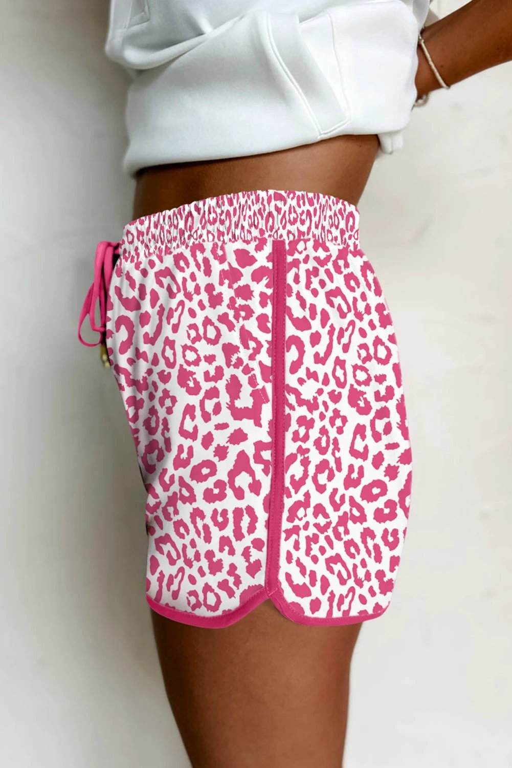 Woman wearing leopard print elastic waistband shorts with lace-up trim and elastic waist, styled casually for everyday comfort.