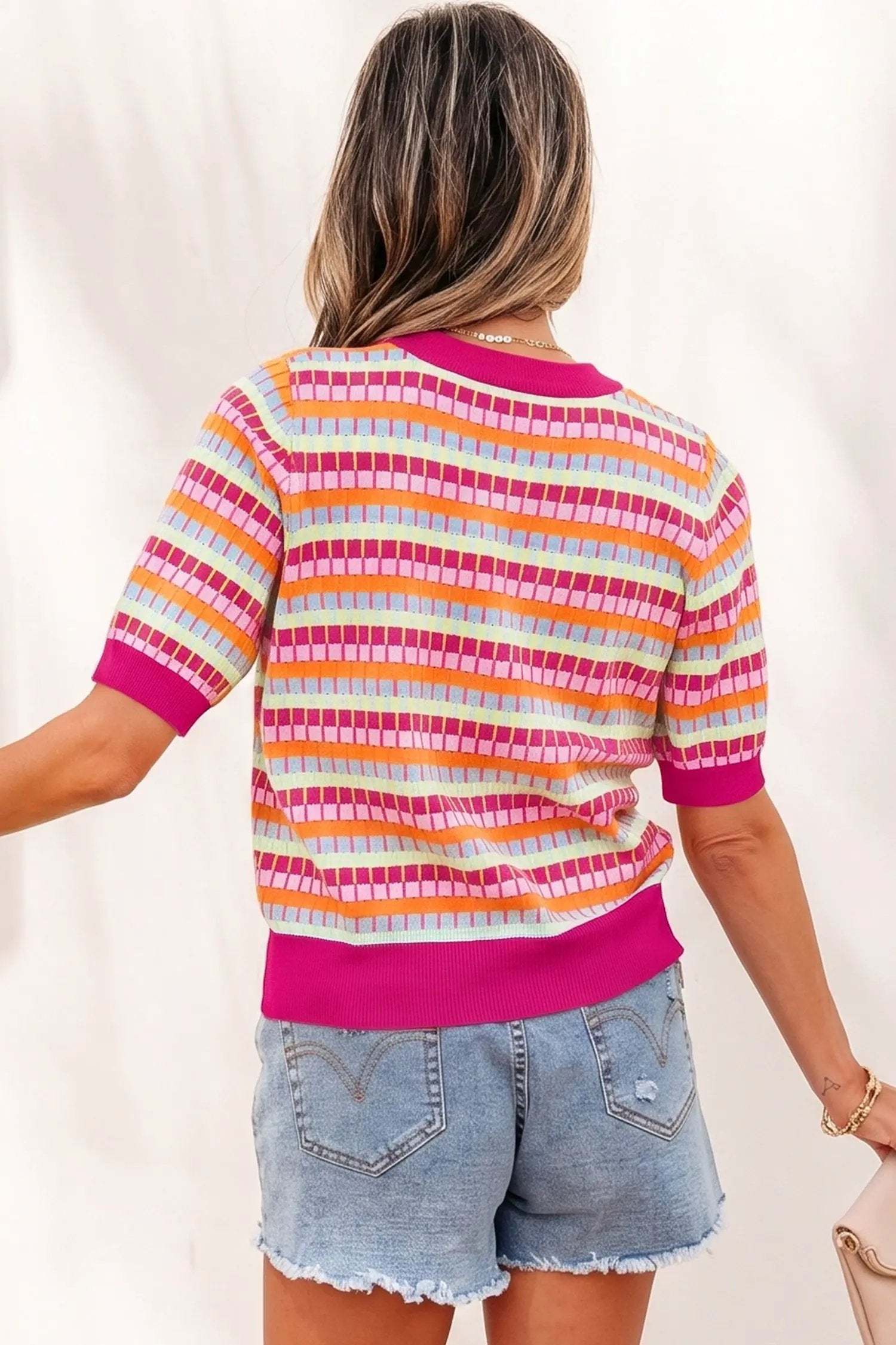 Woman wearing vibrant orange striped knit sweater with short sleeves and fuchsia ribbed neckline