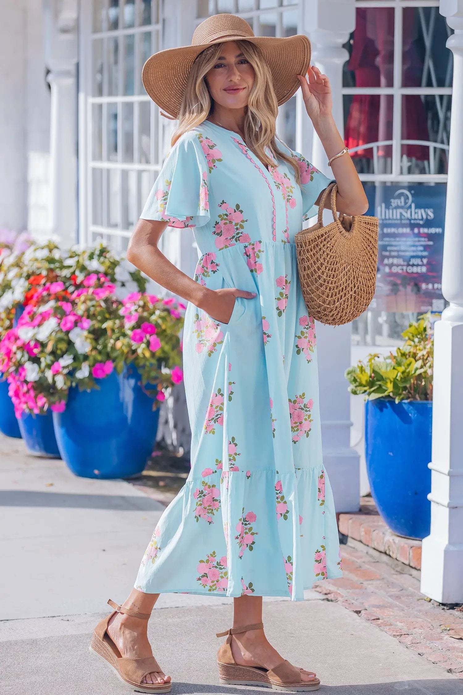 Woman wearing pink floral maxi dress with notched neck and flutter short sleeves