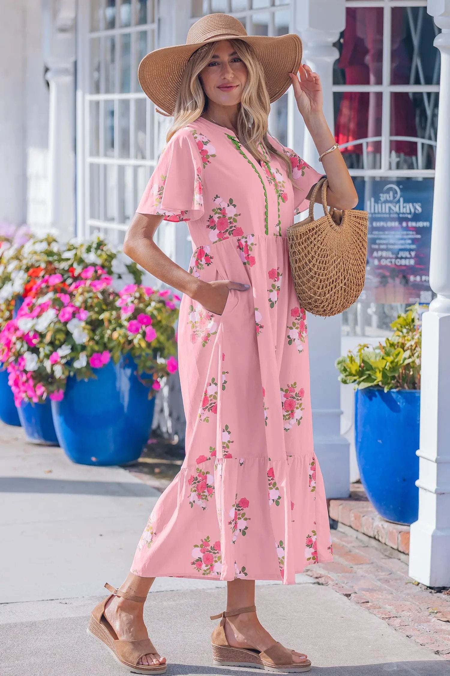 woman wearing pink floral maxi dress with flutter sleeves and notched neckline