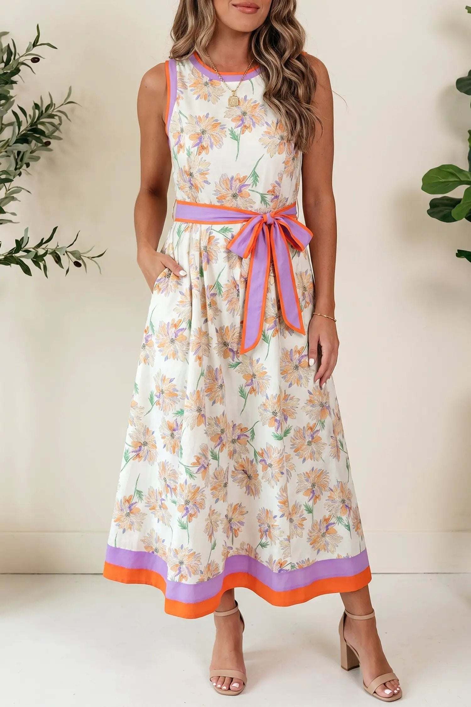 Woman wearing white floral print maxi dress with belted waist and color-block trim at garden party