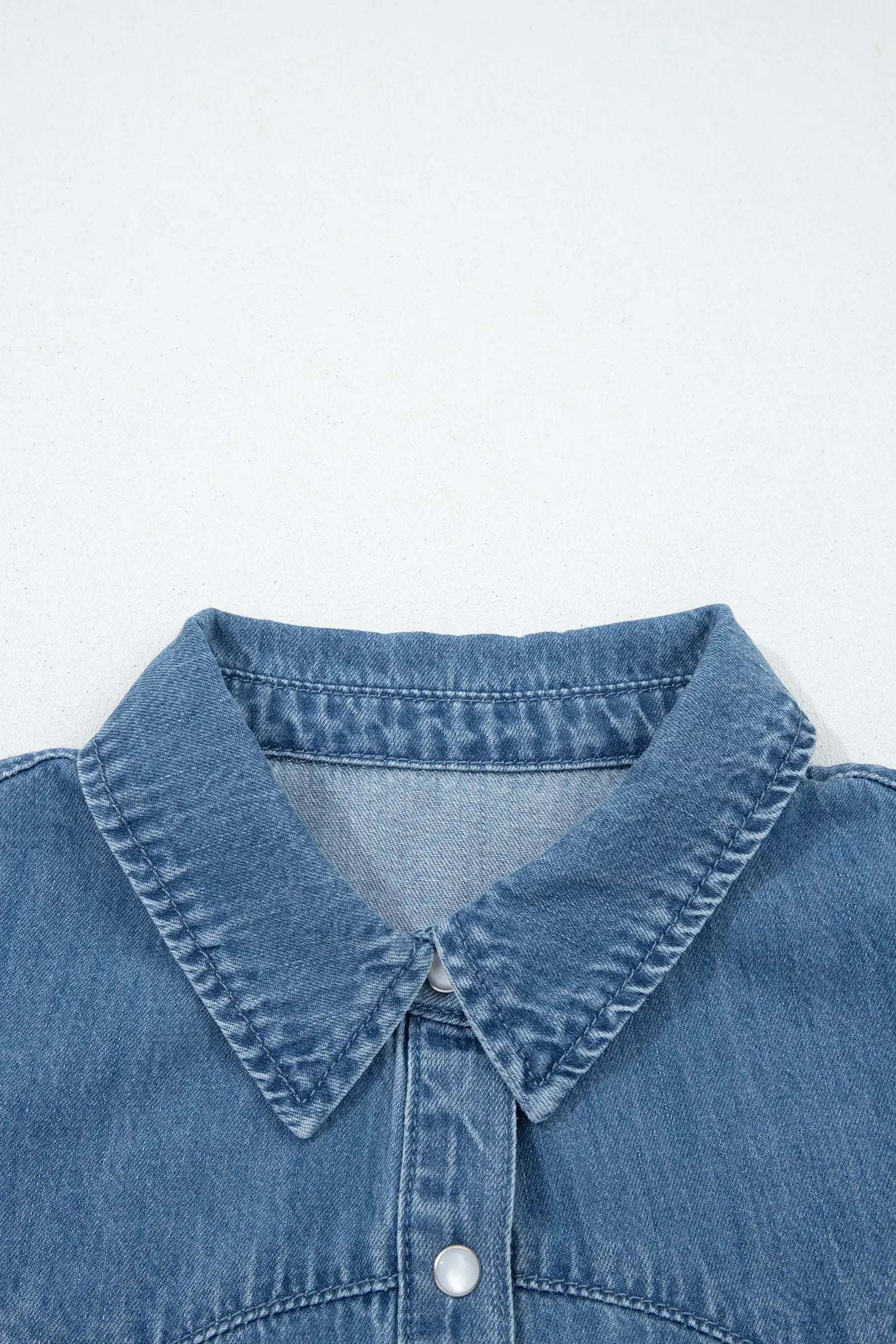 Woman wearing denim ruffled short sleeve shirt with button front and flutter sleeves