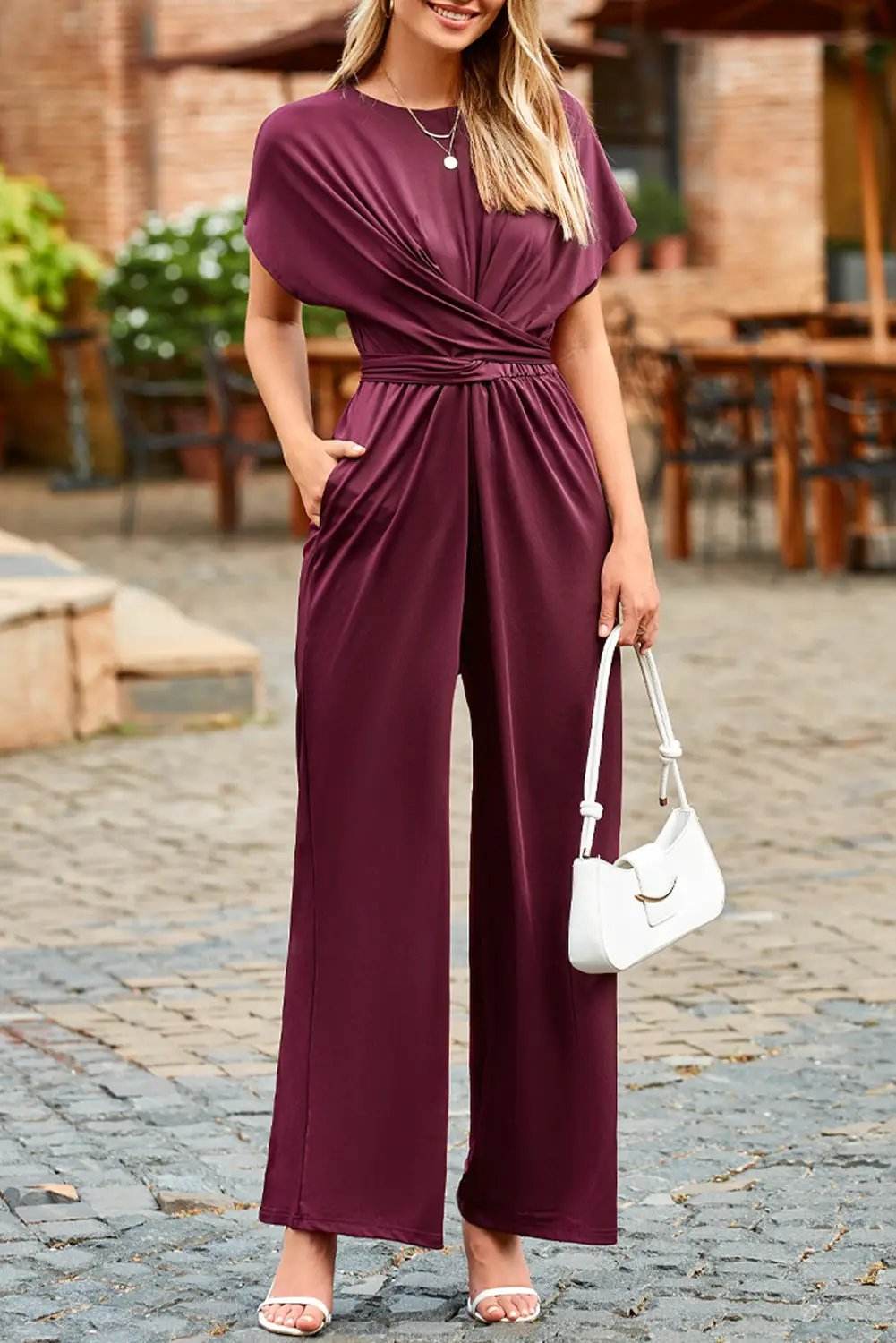 Woman wearing a rich wine knot-waist cap sleeve jumpsuit with wide legs and polished silhouette