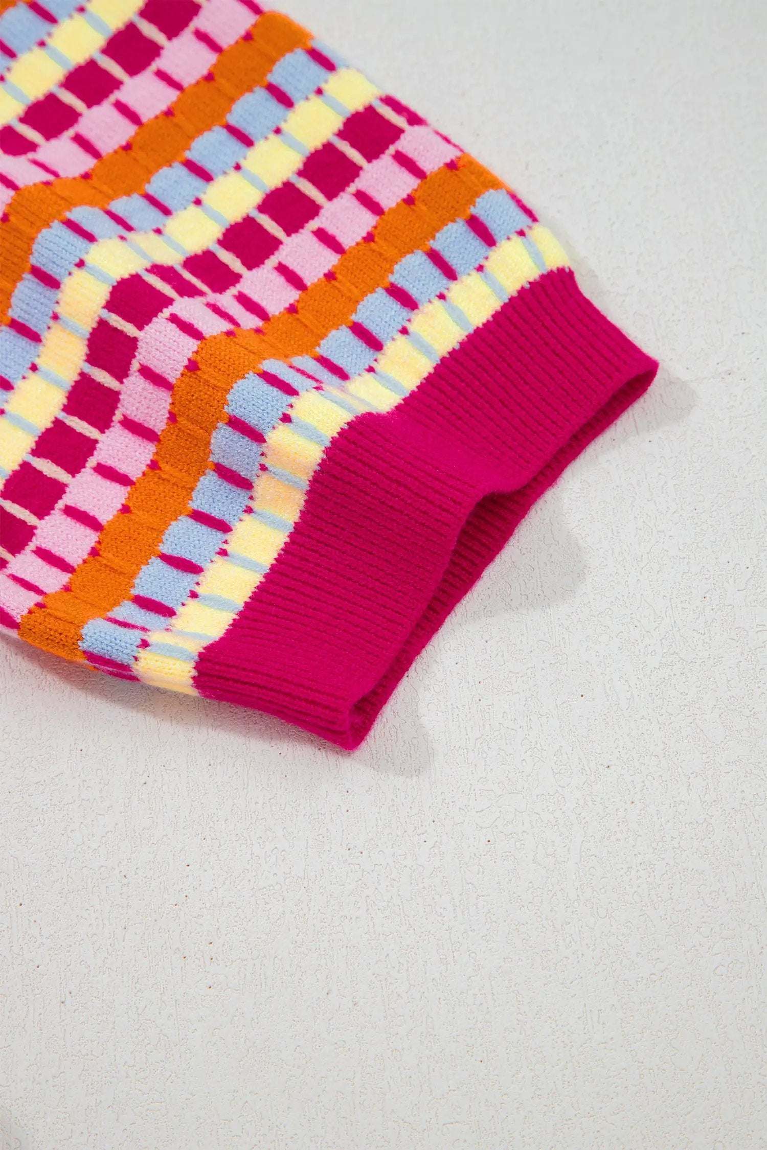 Woman wearing orange striped knit sweater with abstract stripes and fuchsia pink trim