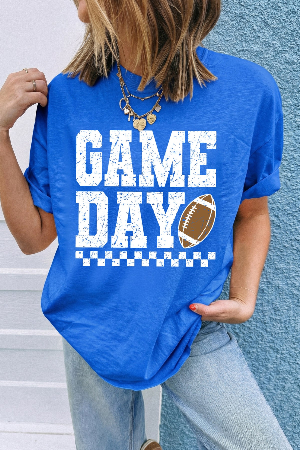 Royal blue crewneck tee with distressed white GAME DAY text, a checkered stripe accent, and a football graphic on the chest