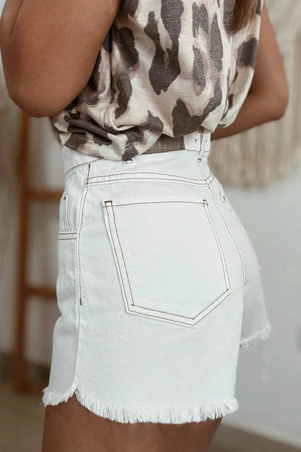 Woman wearing casual high waist denim shorts with raw hem outdoors