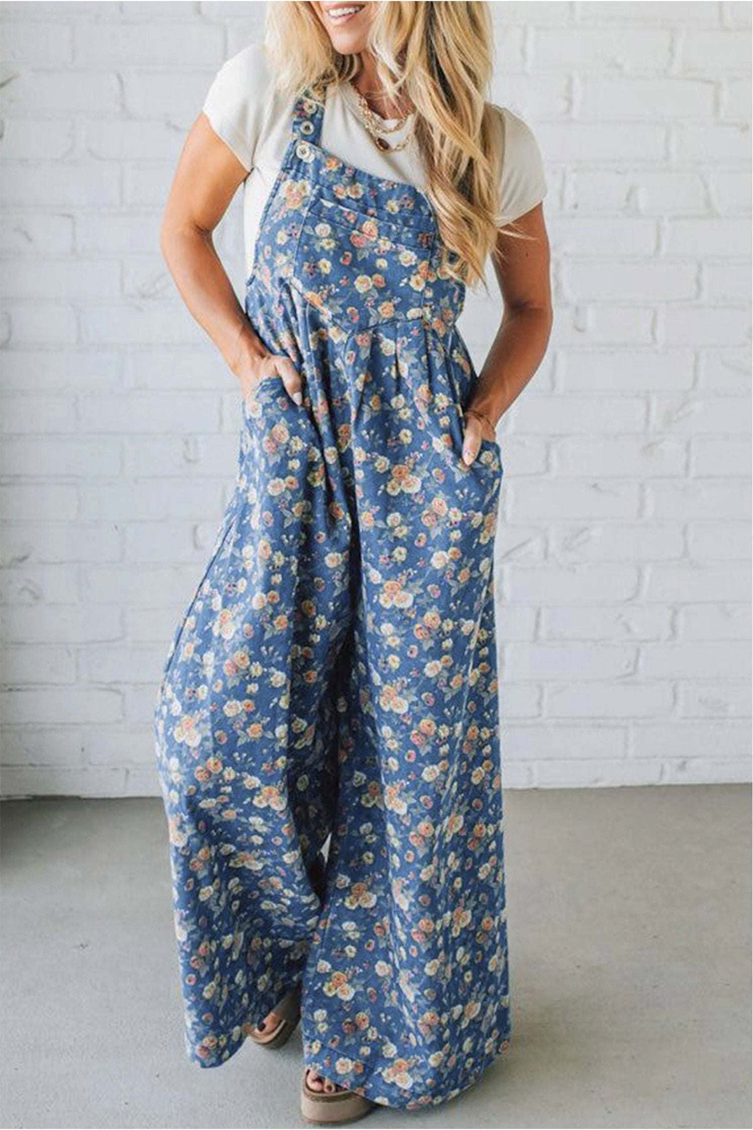 Woman wearing floral denim overalls with wide-leg silhouette and adjustable straps standing outdoors