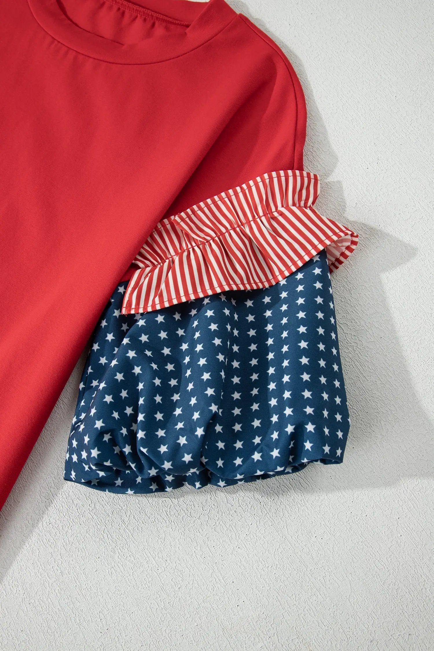 Woman wearing Patriotic puff sleeve top with fiery red stars stripes and American flag print