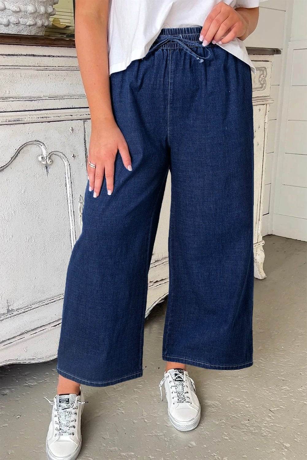 Plus size model wearing indigo drawstring high waist wide leg jeans showcasing comfortable and stylish fit