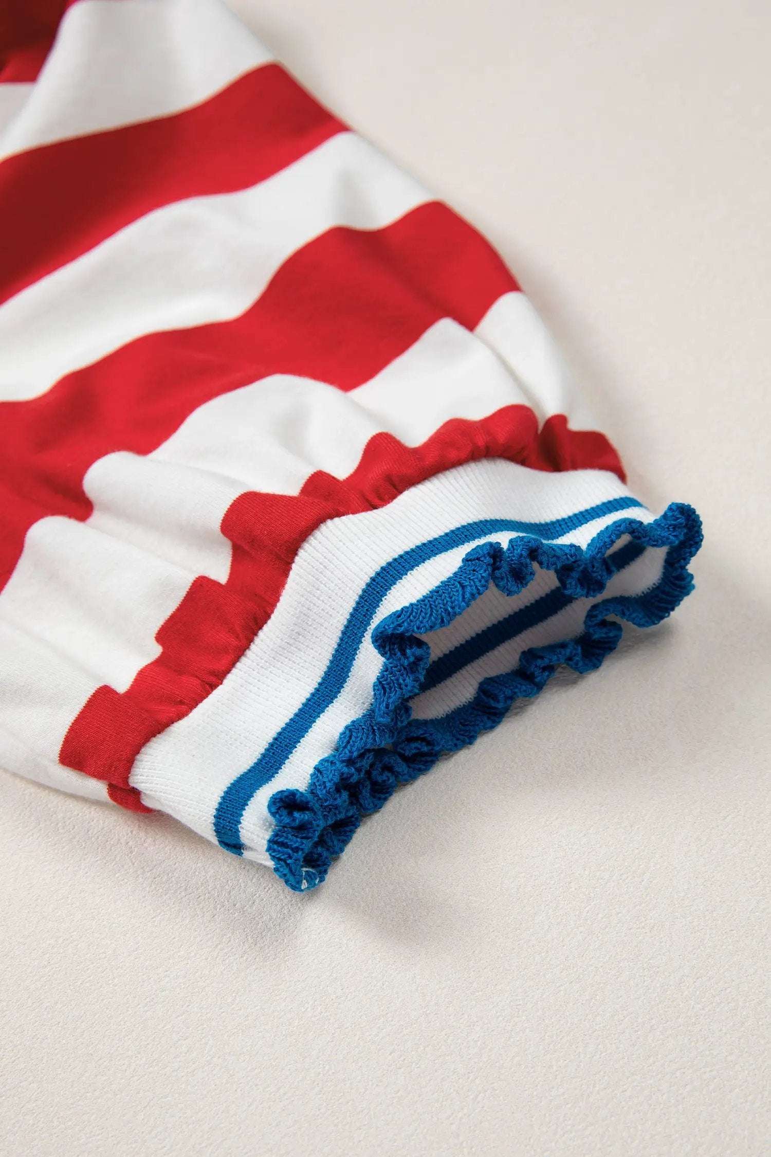 Close-up of a red, white, and blue striped garment with ruffled trim on a light background