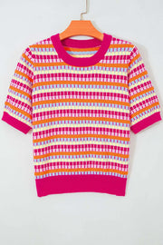 Woman wearing vibrant orange striped knit sweater with short sleeves and abstract stripes