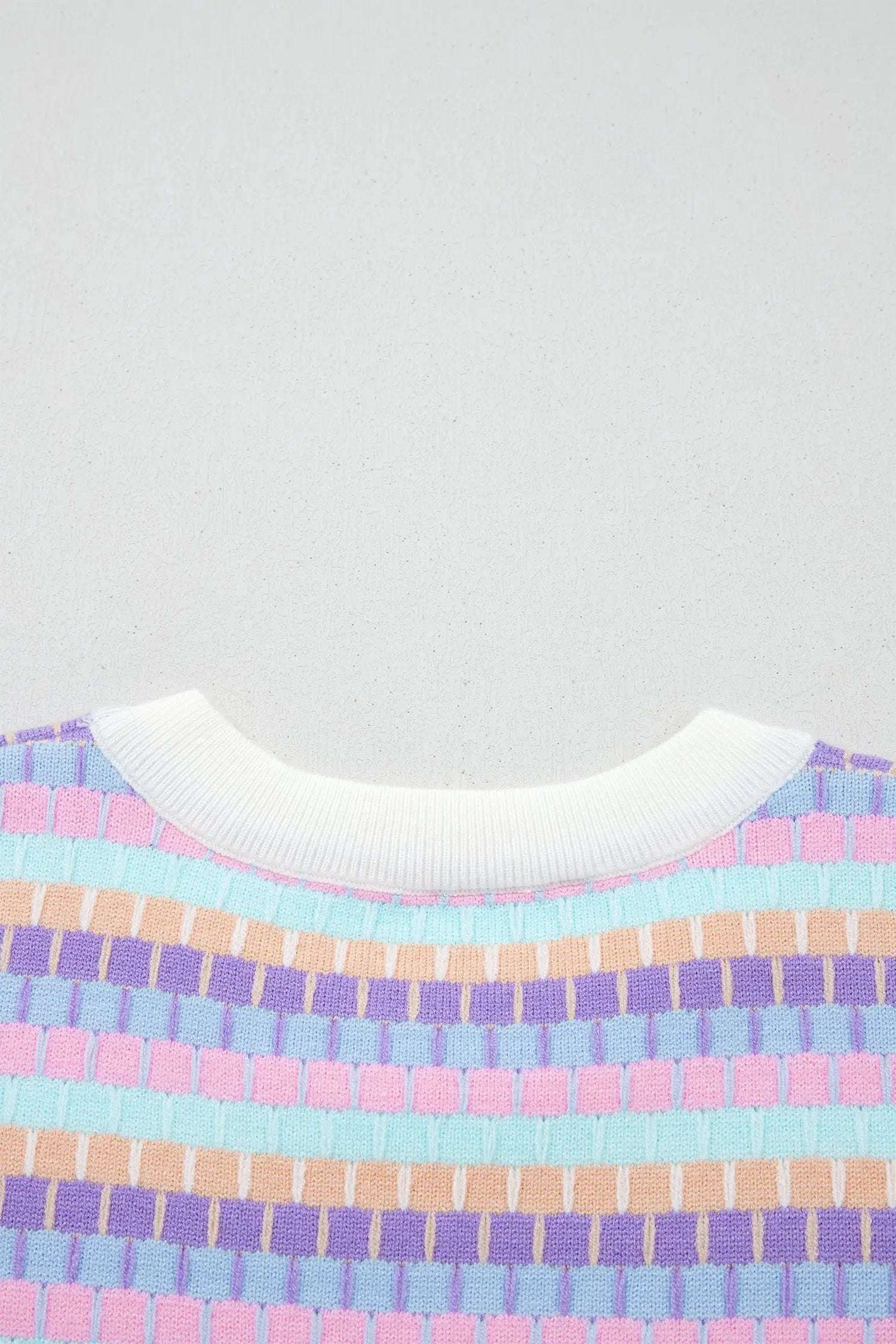 Woman wearing vibrant orange striped knit sweater with short sleeves and abstract stripes